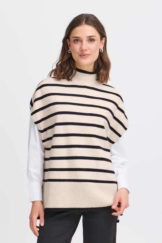 Woman wearing a cream and black striped sweater vest over a white shirt on a light gray background