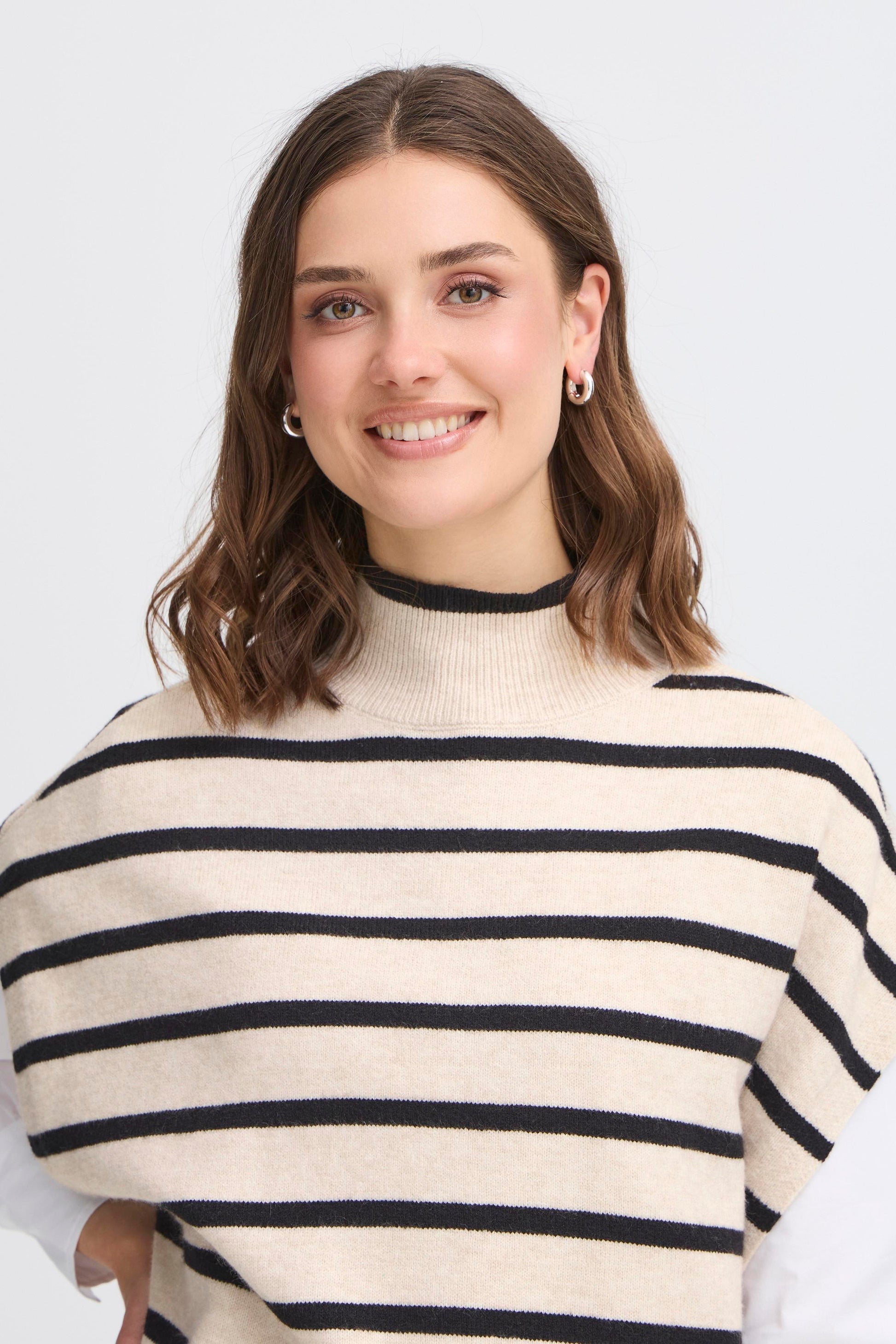 Woman wearing a cream and navy striped sweater against a white background