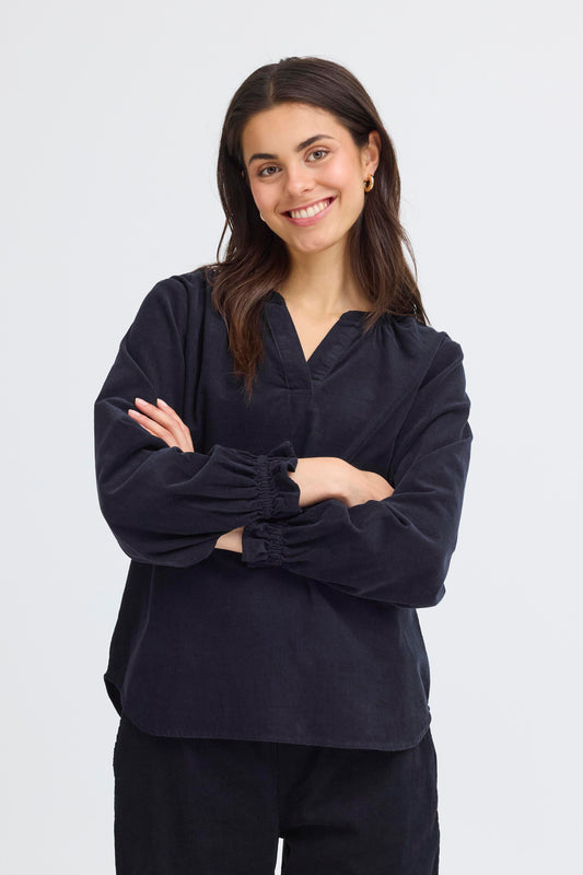 Woman wearing a navy blue outfit with a plain background