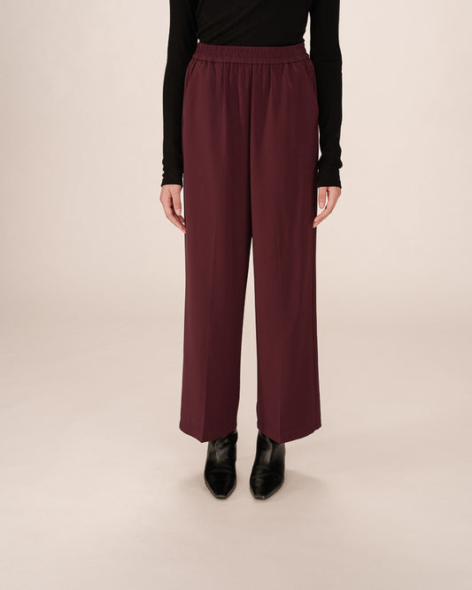 Maroon wide-leg pants worn by a person on a beige background