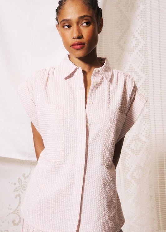 Woman wearing a textured white shirt against a neutral background
