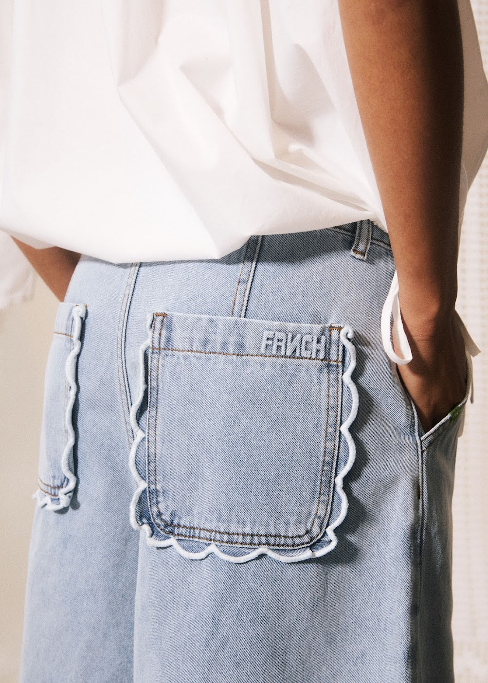 Light blue jeans with scalloped pocket edge and 'FAVICH' branding.
