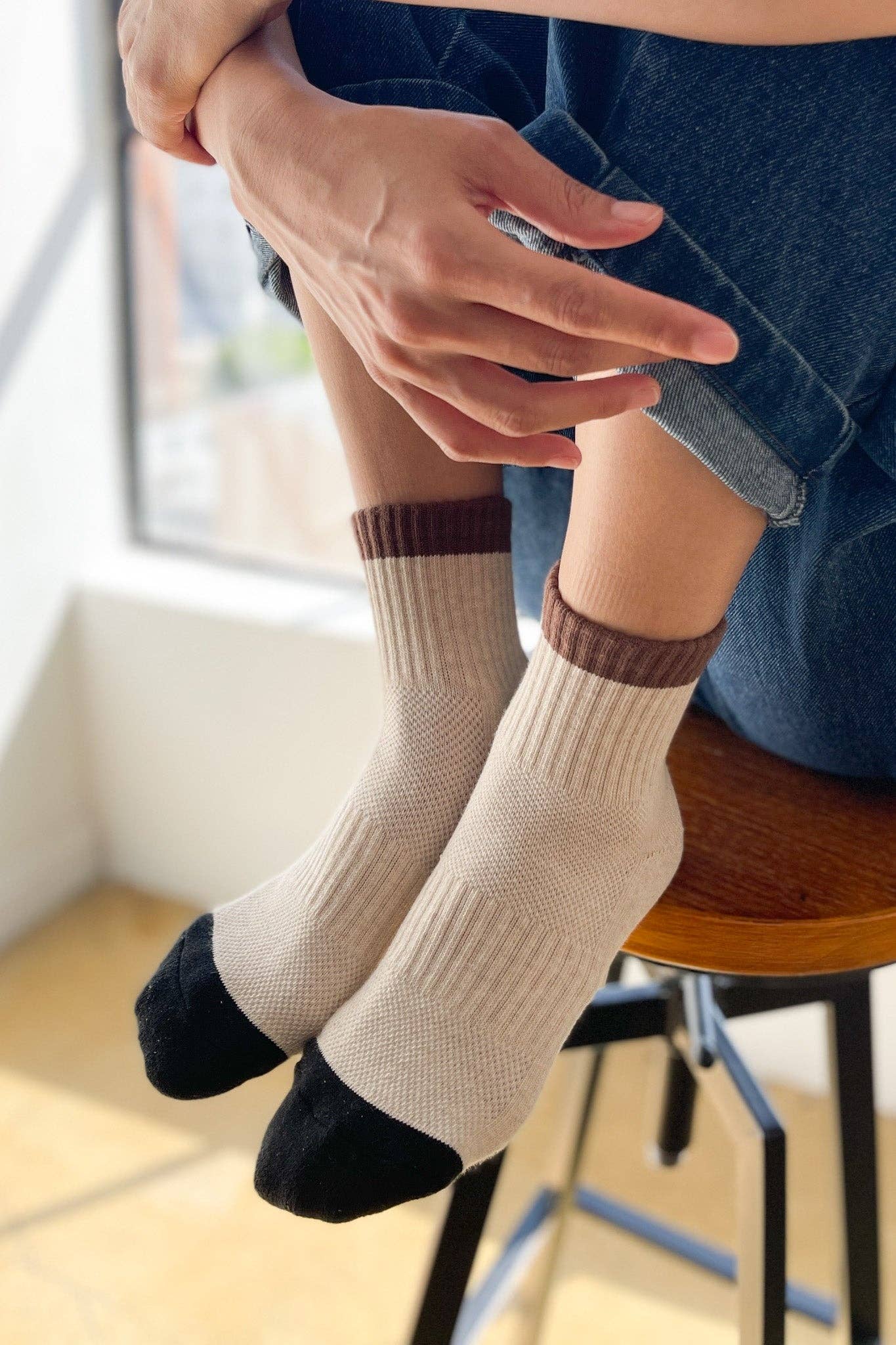 Person wearing beige socks with brown accents sitting on a chair.