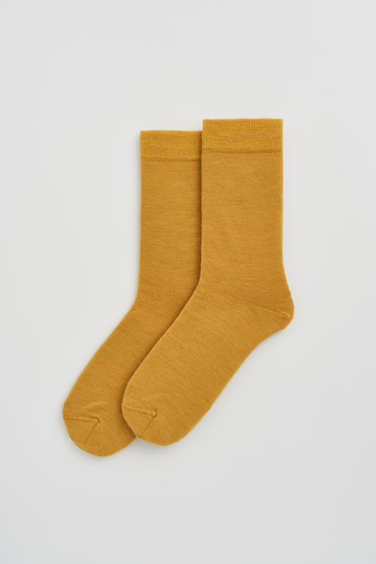 Pair of mustard yellow socks on a light gray background