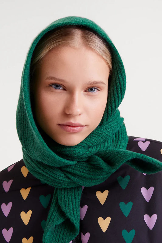 Woman wearing a green scarf with a plain background