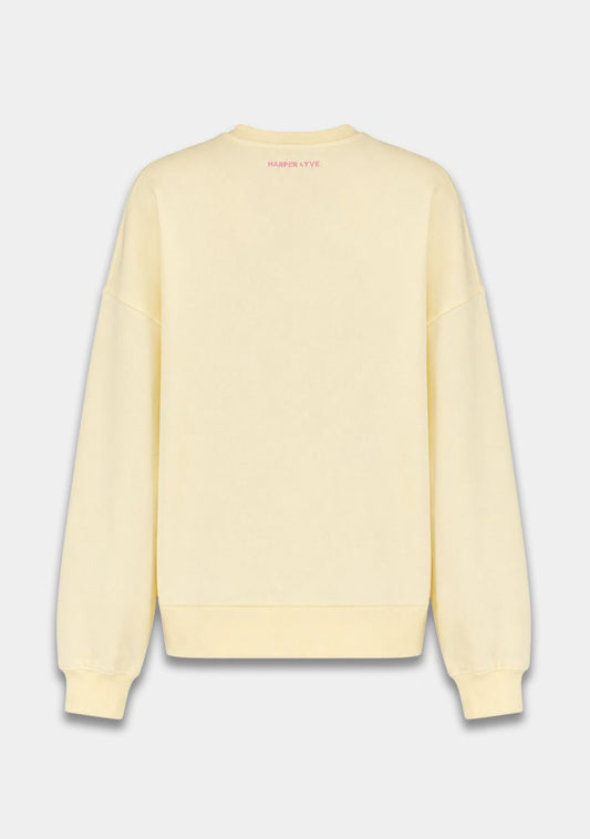A pale yellow crewneck sweatshirt shown from the back, featuring a small pink 'SWEATERS-OUTLET' logo printed at the inner neckline, set against a light gray background.