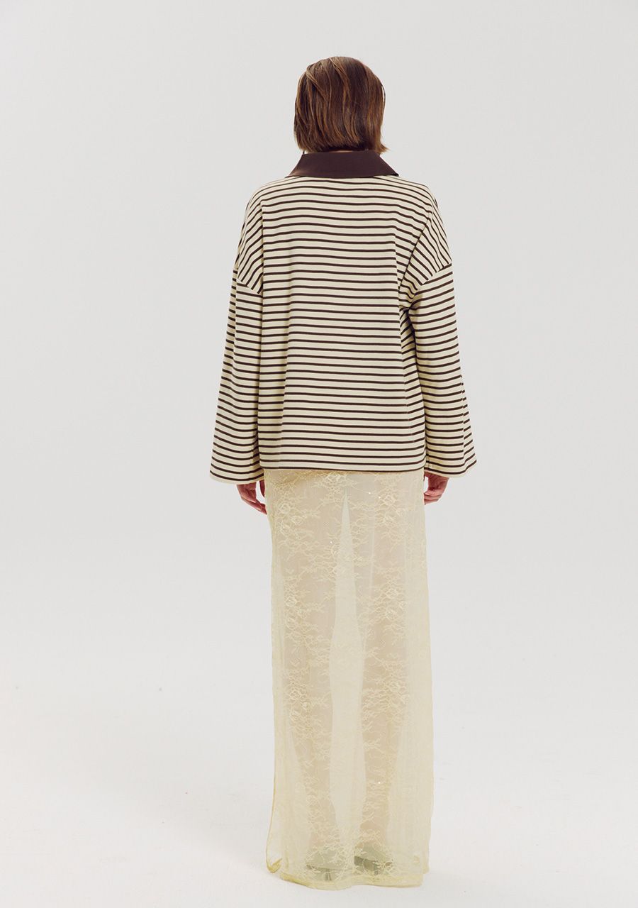 A model viewed from the back wearing a brown and cream striped long-sleeve top with a dark brown collar, paired with a cream lace maxi skirt, against a plain light gray background.