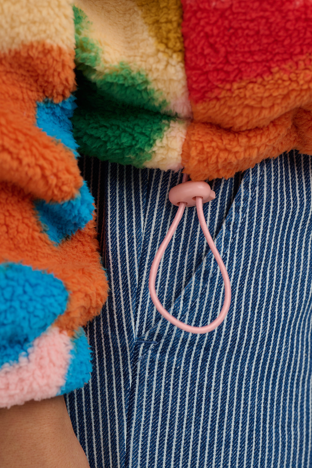 Close-up of colorful fleece jacket with a pink lanyard hanging from a pocket.