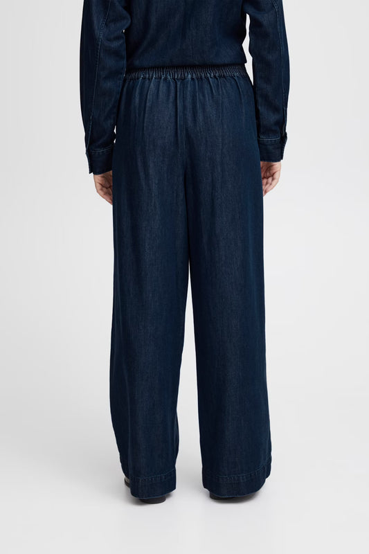Person wearing dark blue wide-leg pants on a white background