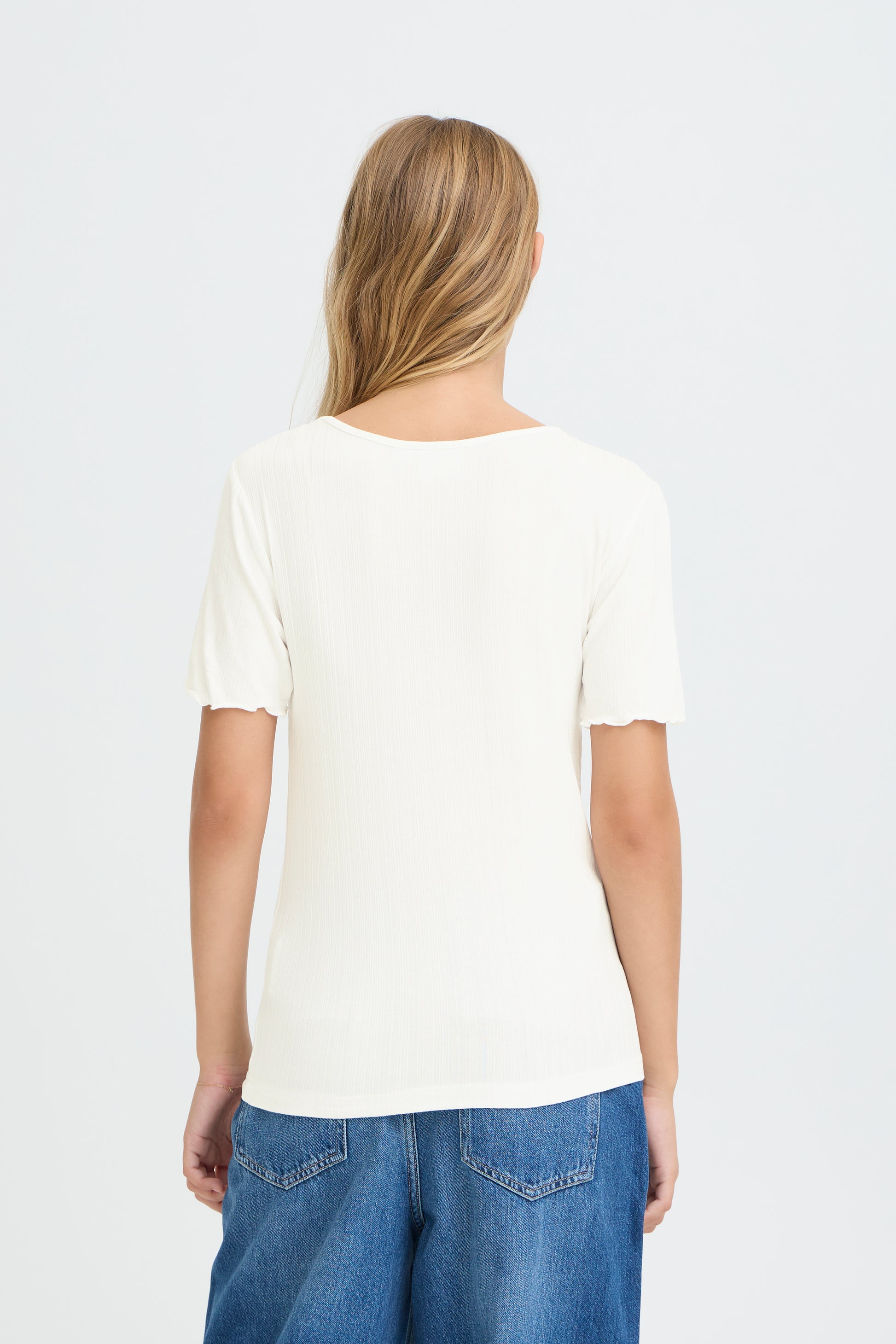 Person wearing a plain white t-shirt and blue jeans on a light gray background