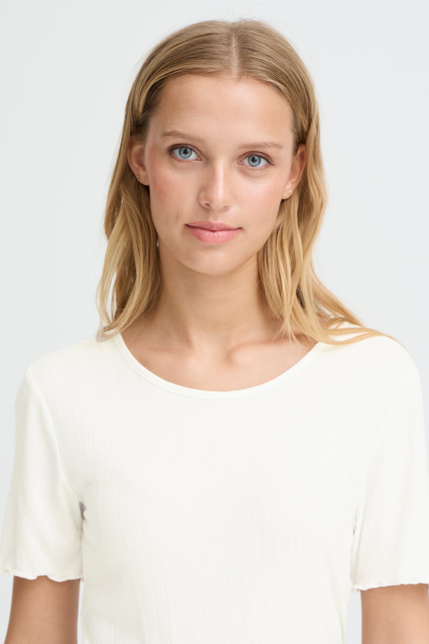 Woman wearing a white t-shirt against a plain background