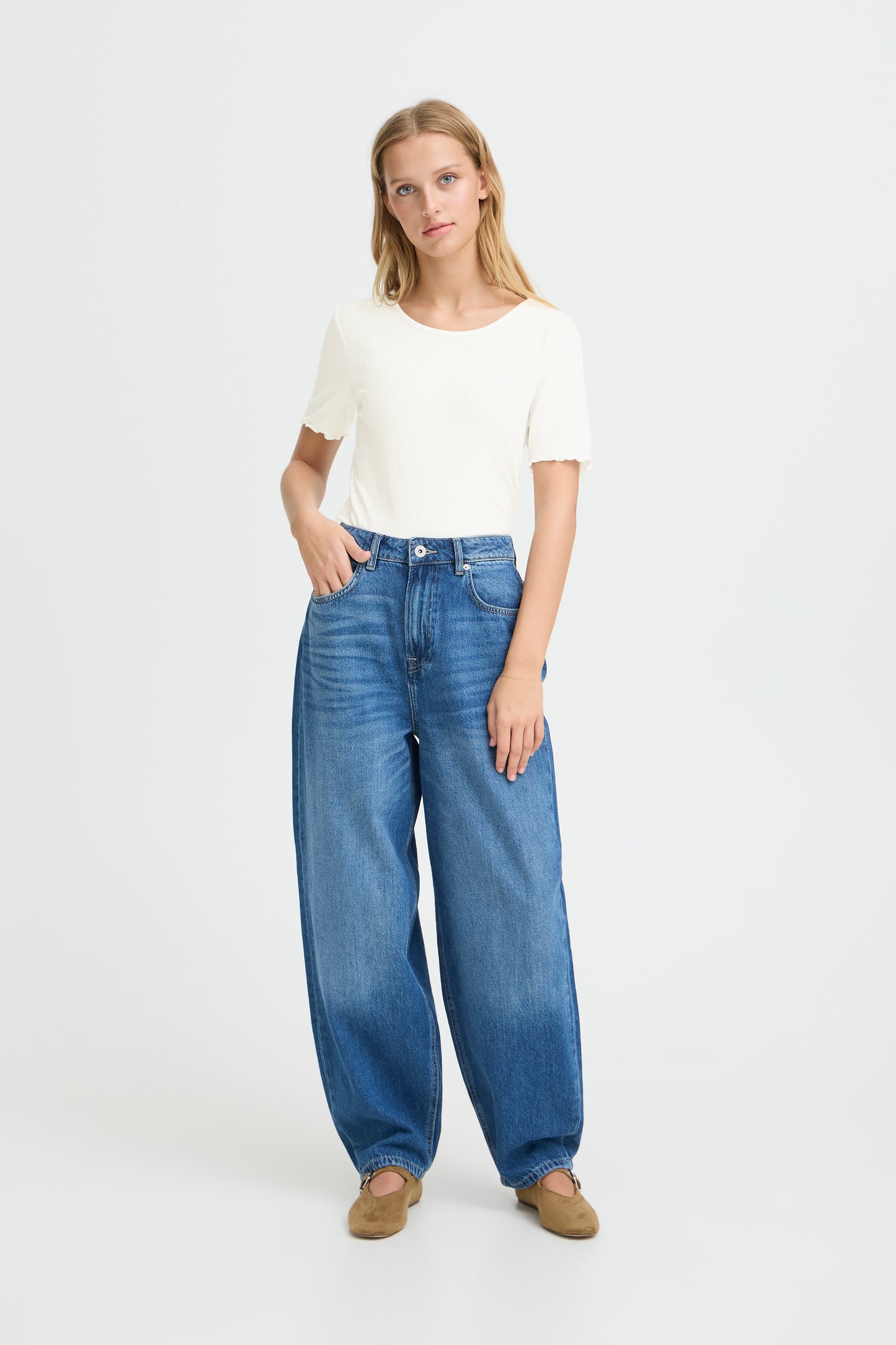 Woman wearing blue jeans and a white top on a white background