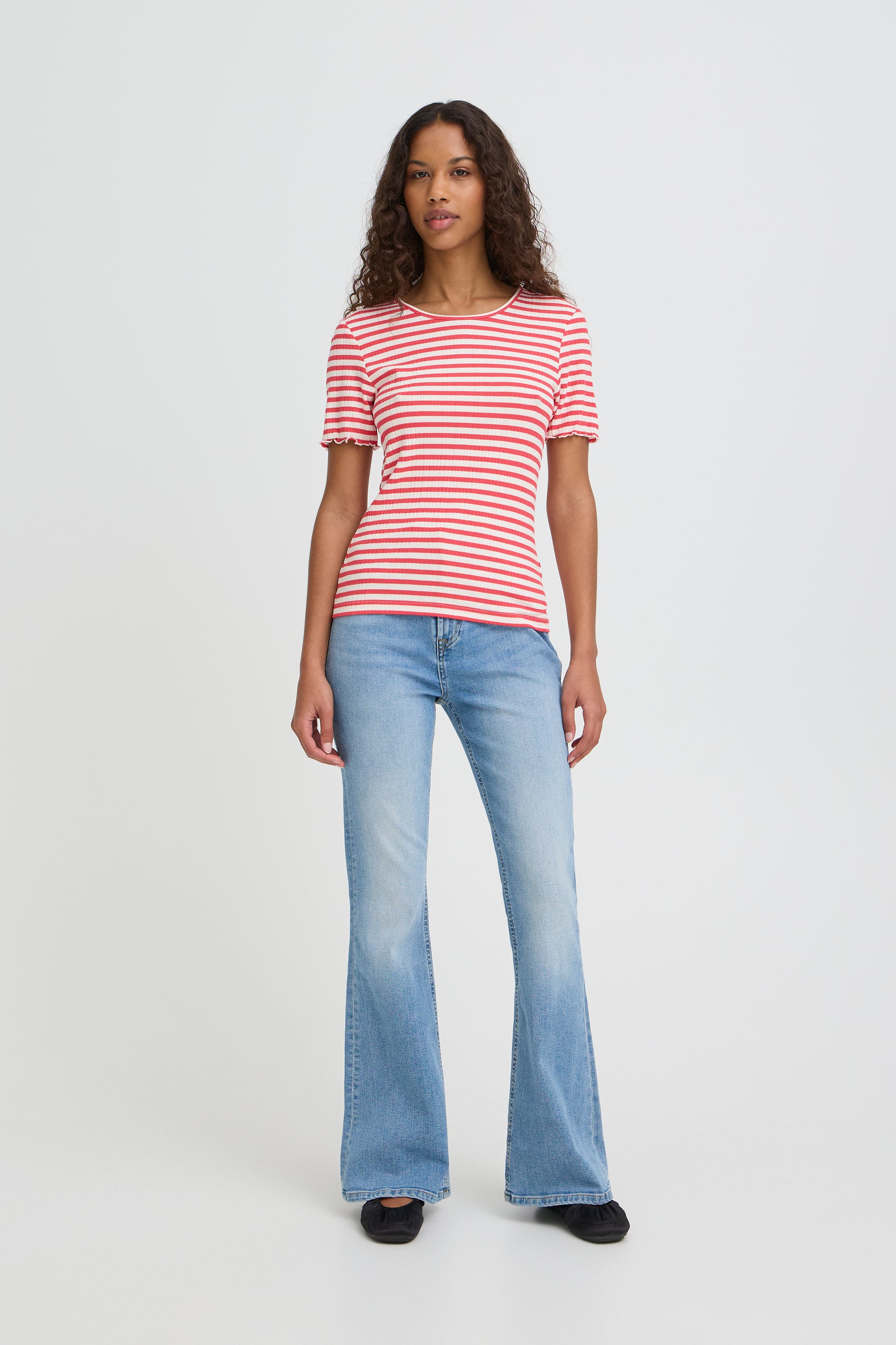 Woman wearing a red and white striped shirt and blue jeans on a white background