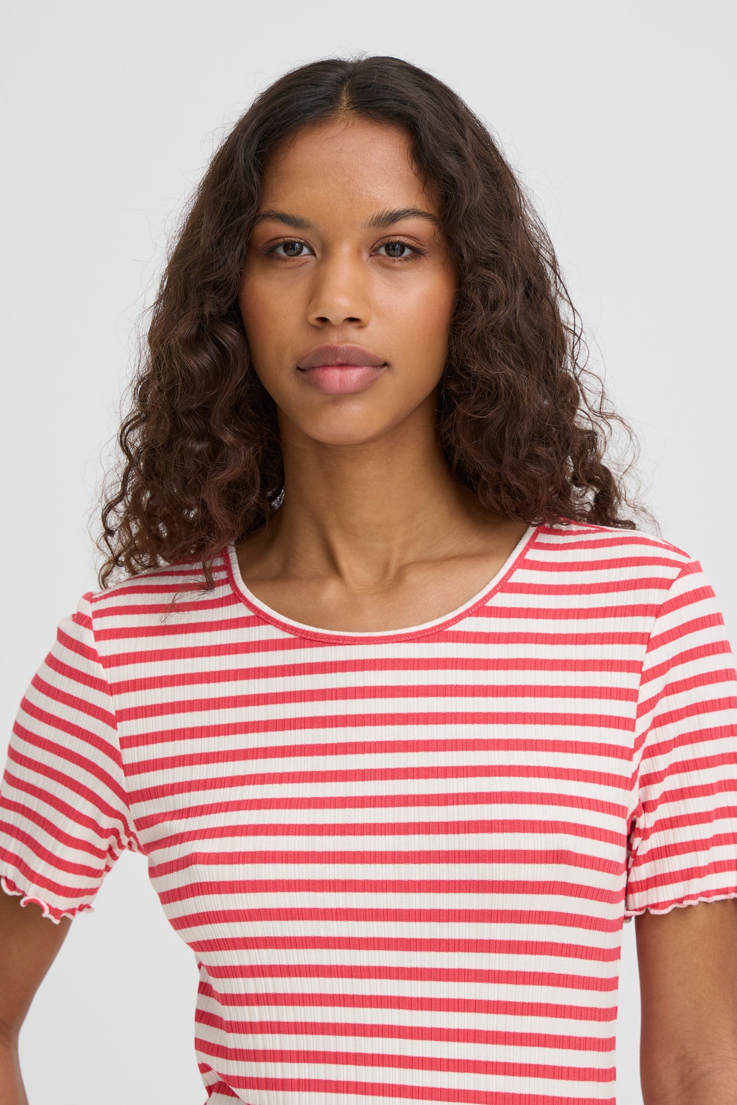 Woman wearing a red and white striped shirt against a plain background
