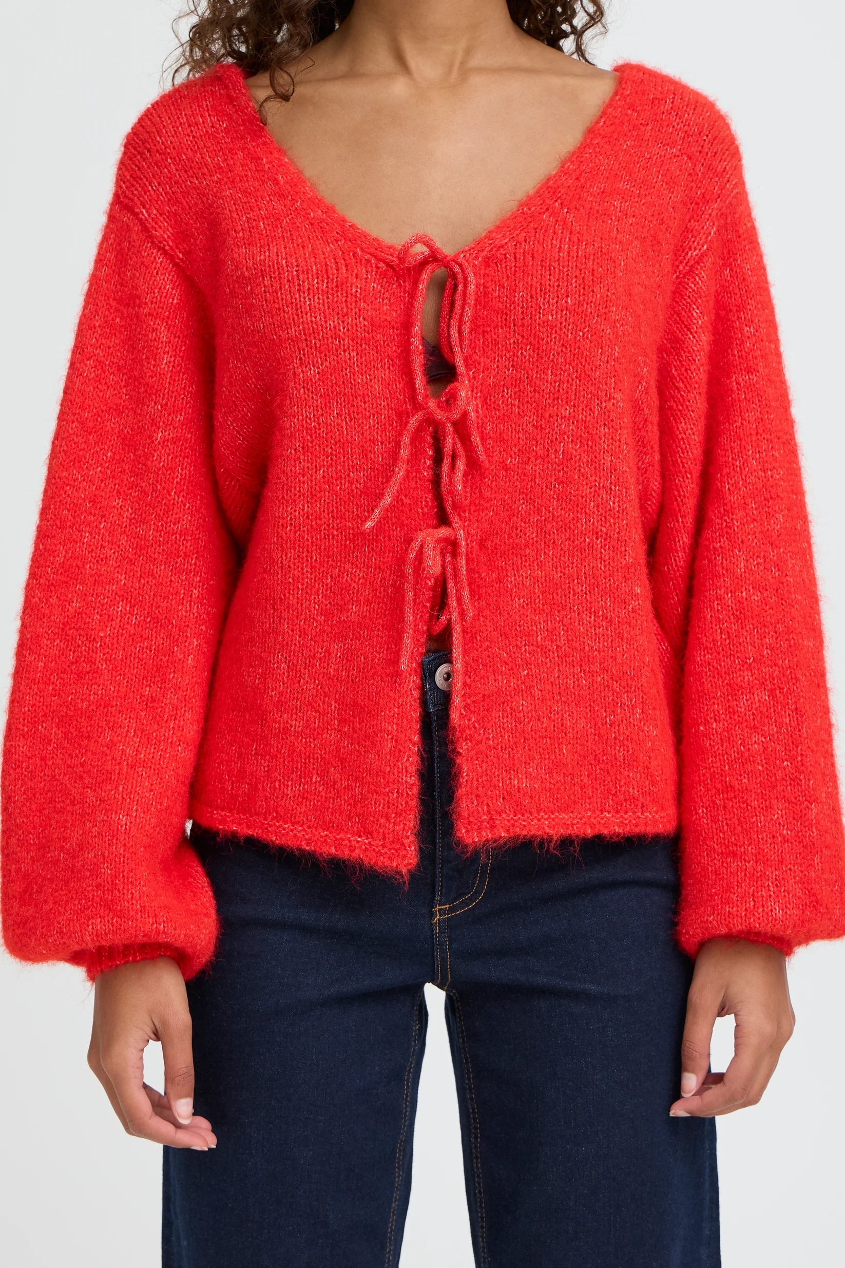 Red knitted cardigan with a tie front on a plain background