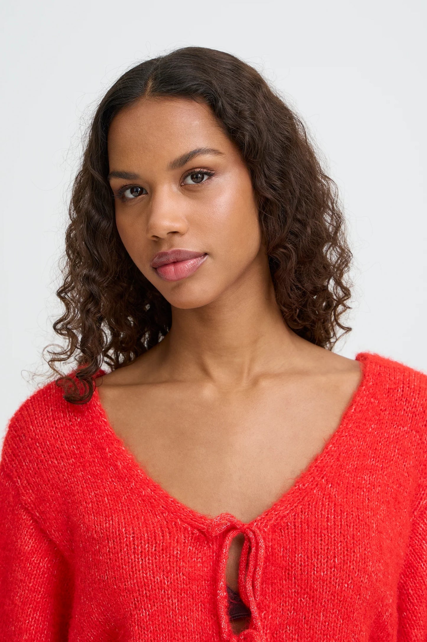 Woman wearing a red sweater against a white background