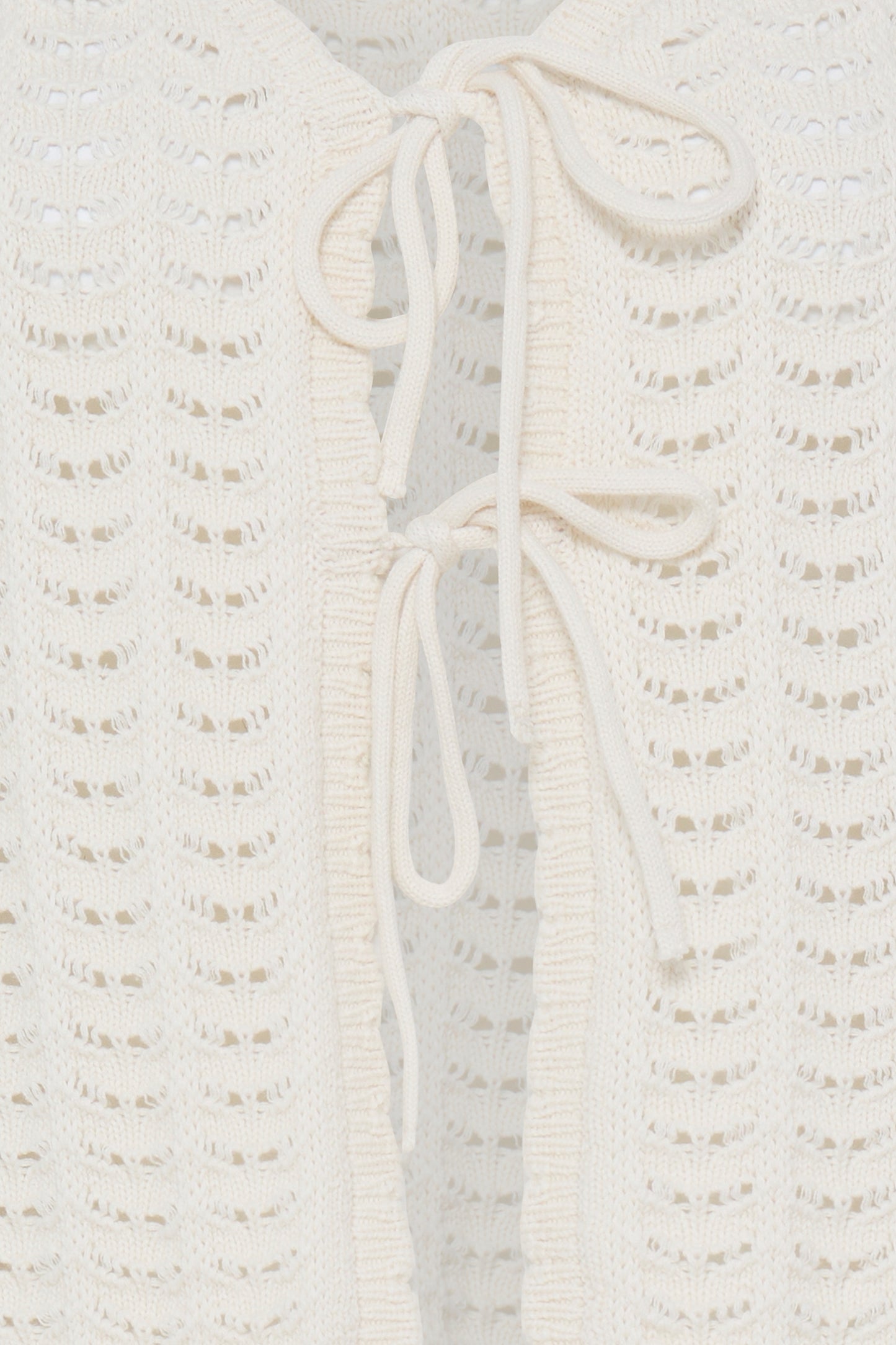 Close-up of a textured white garment with a tie detail on a light gray background
