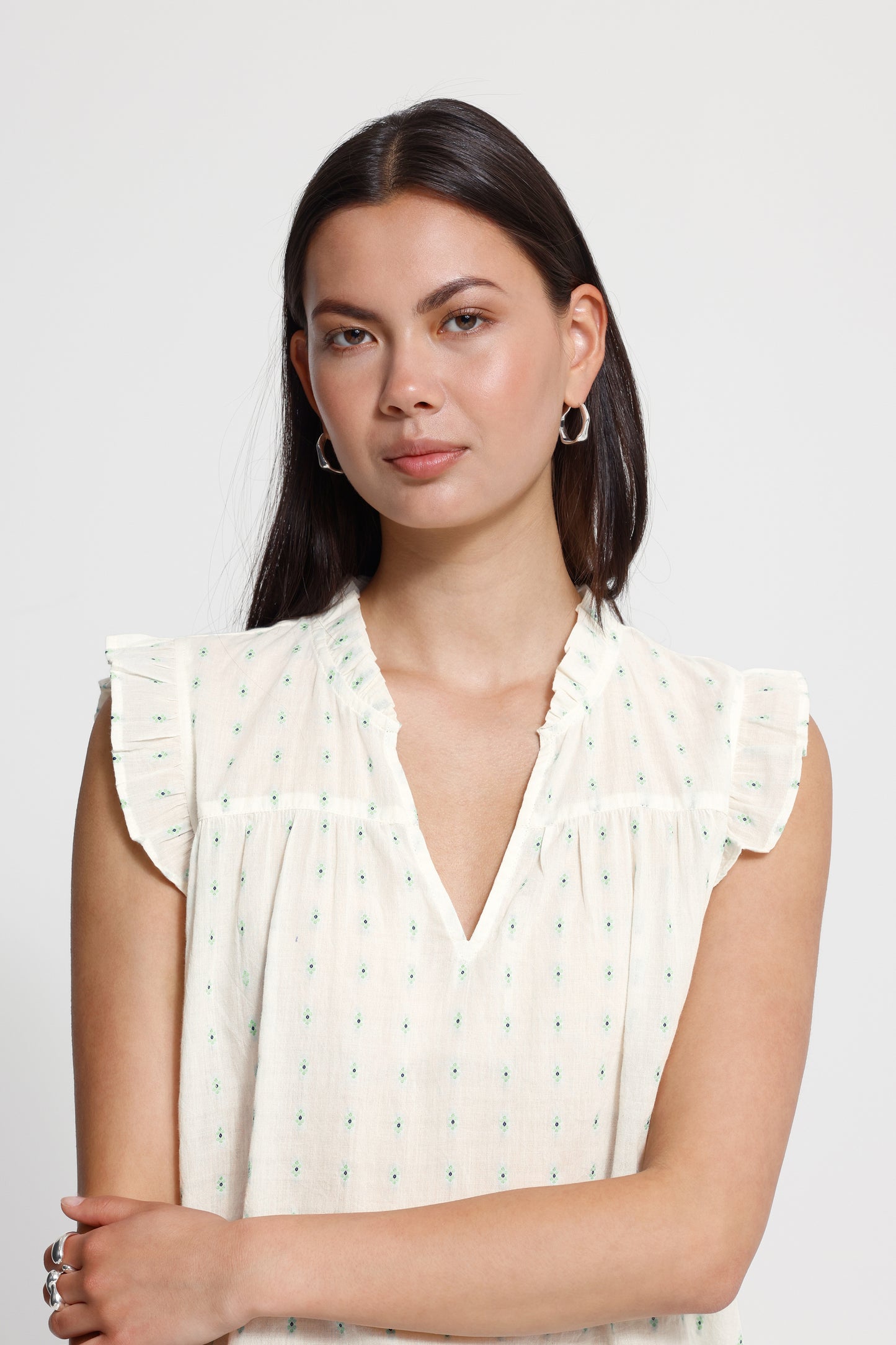 Woman wearing a white blouse with ruffled sleeves on a plain background