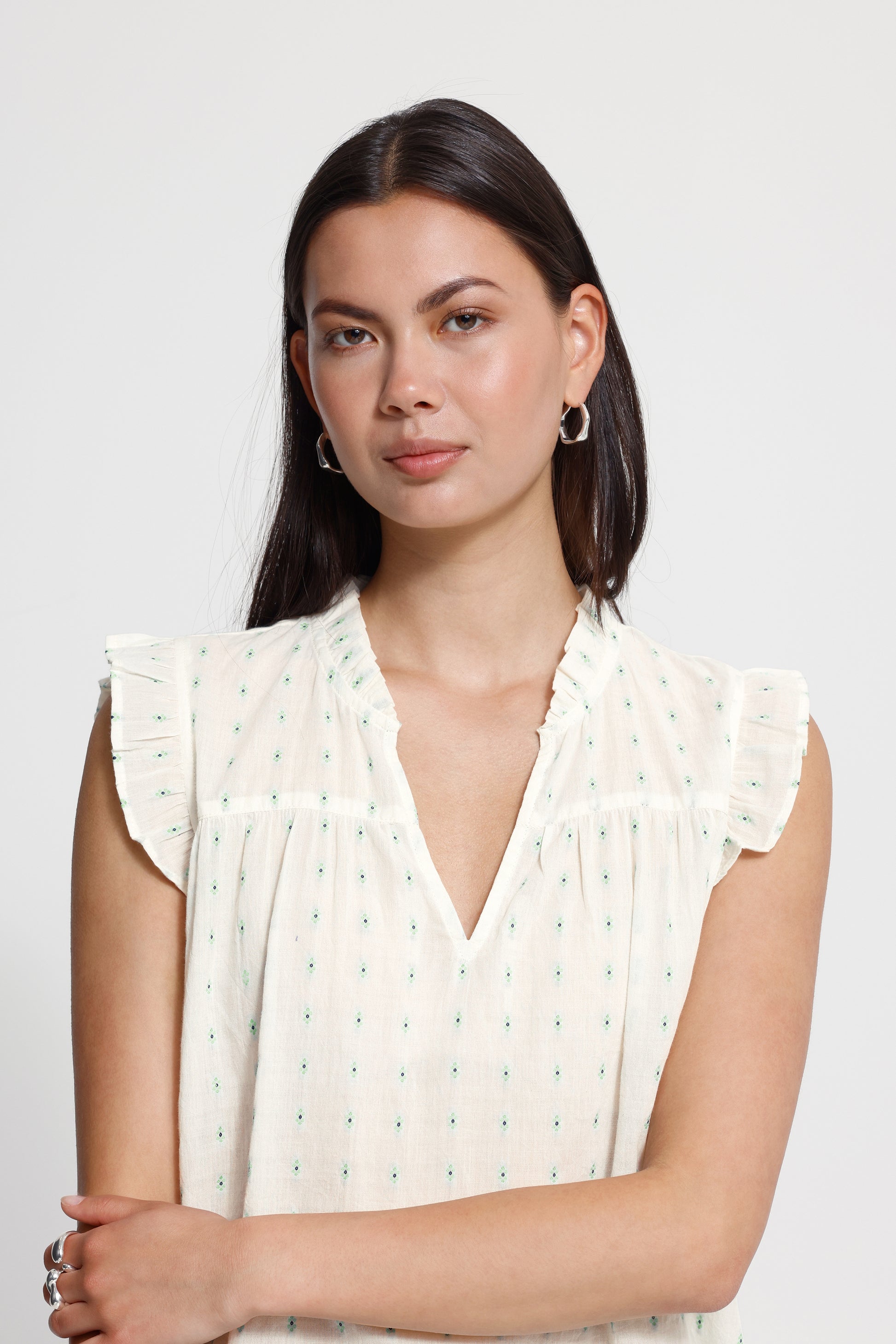Woman wearing a white blouse with ruffled sleeves on a plain background