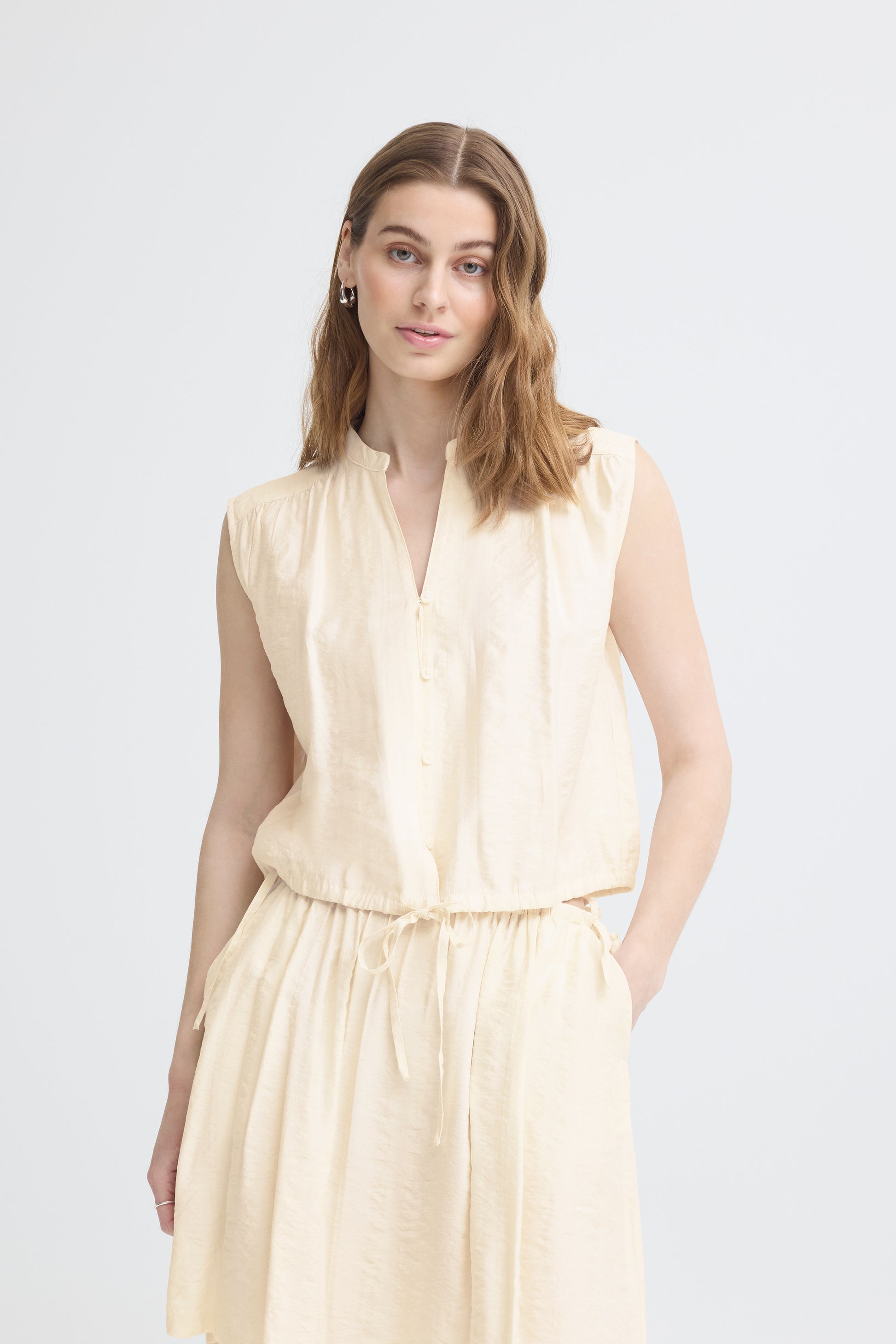 Woman wearing a beige sleeveless dress on a white background
