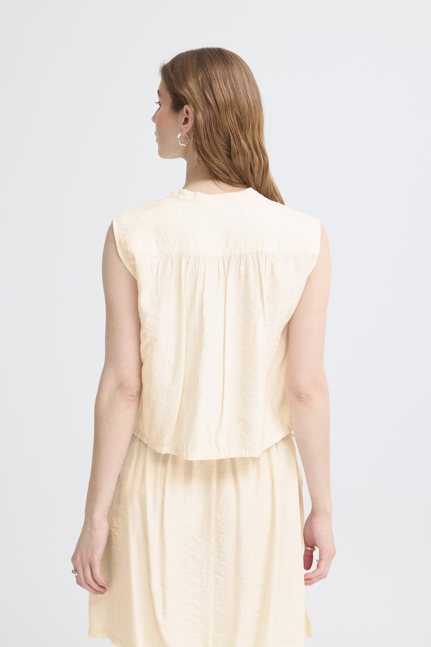 Woman wearing a light-colored dress against a white background