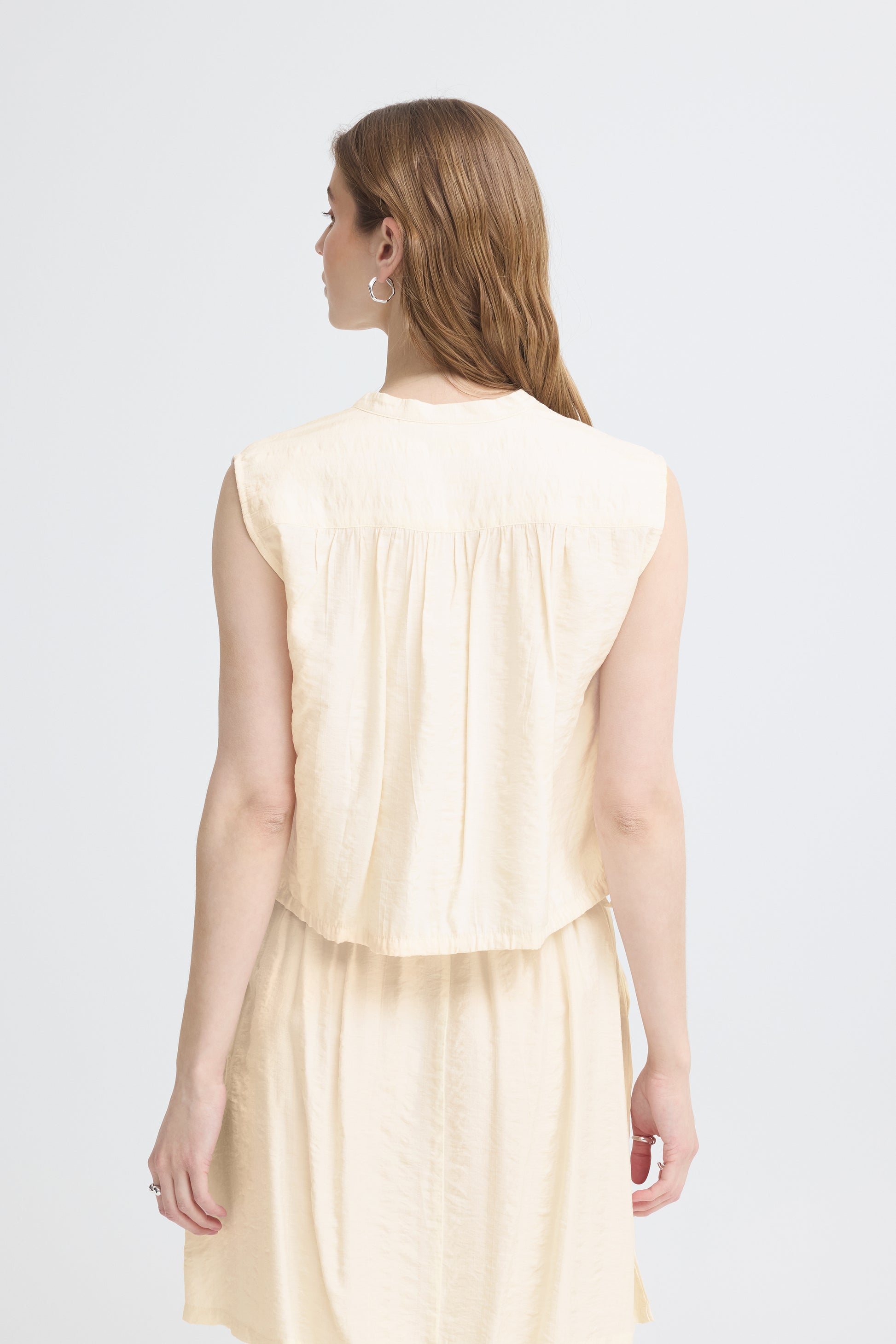 Woman wearing a light-colored dress against a white background