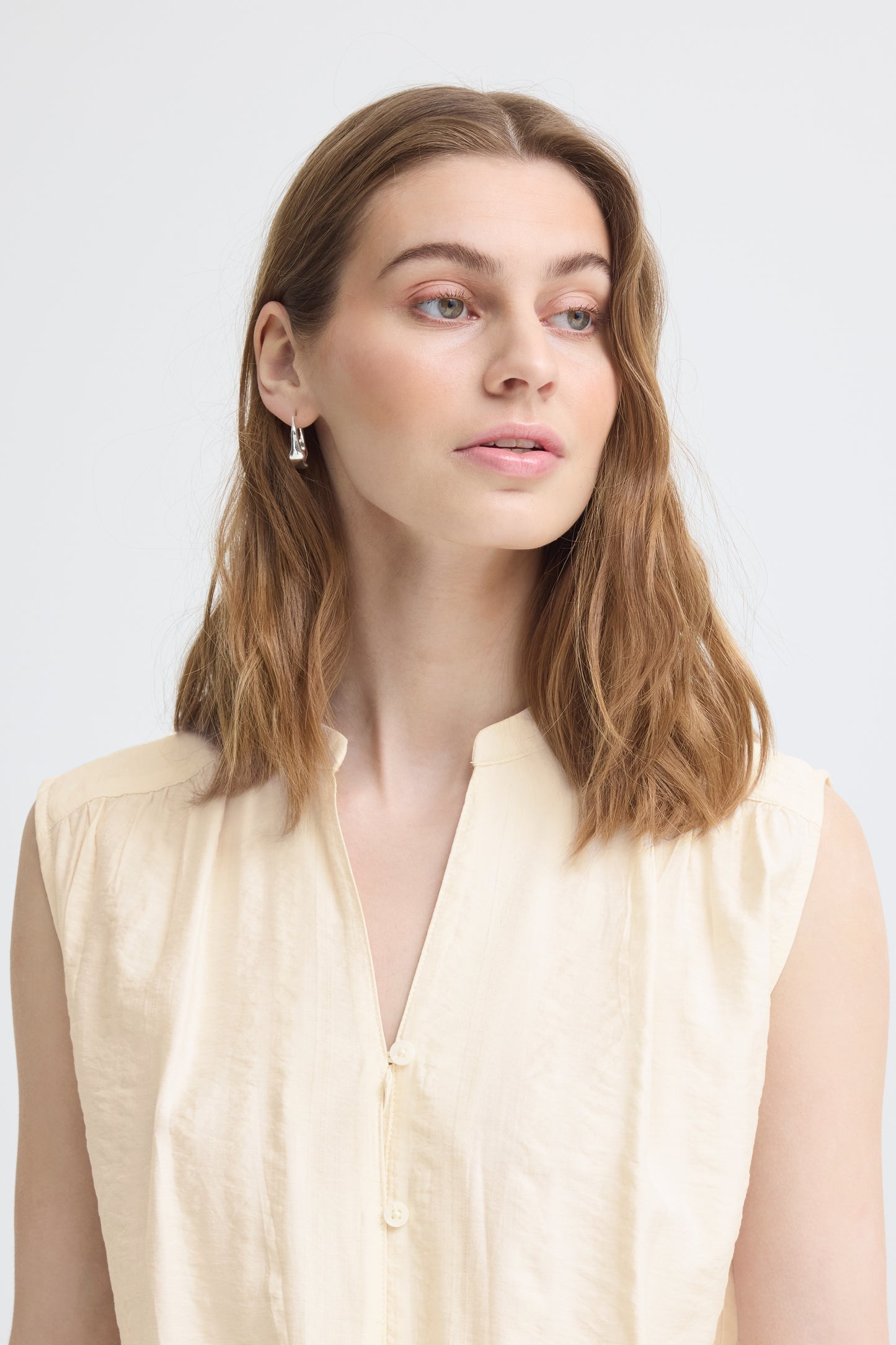 Woman wearing a light-colored blouse against a plain background