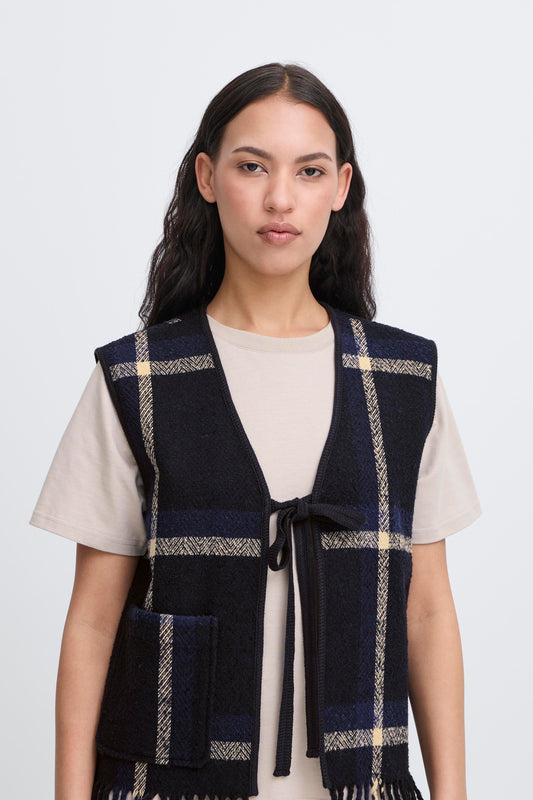 Woman wearing a navy checkered vest over a white shirt on a light gray background