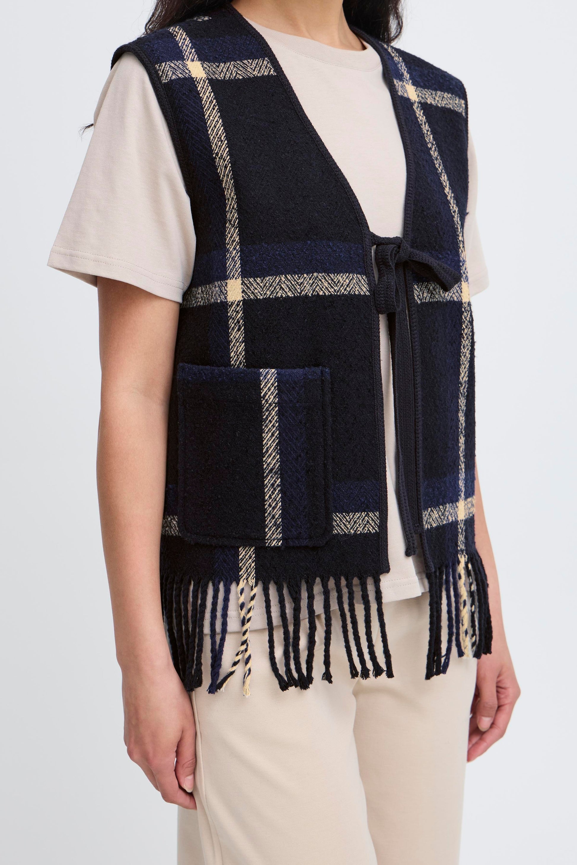 Person wearing a navy plaid vest with white accents on a plain background