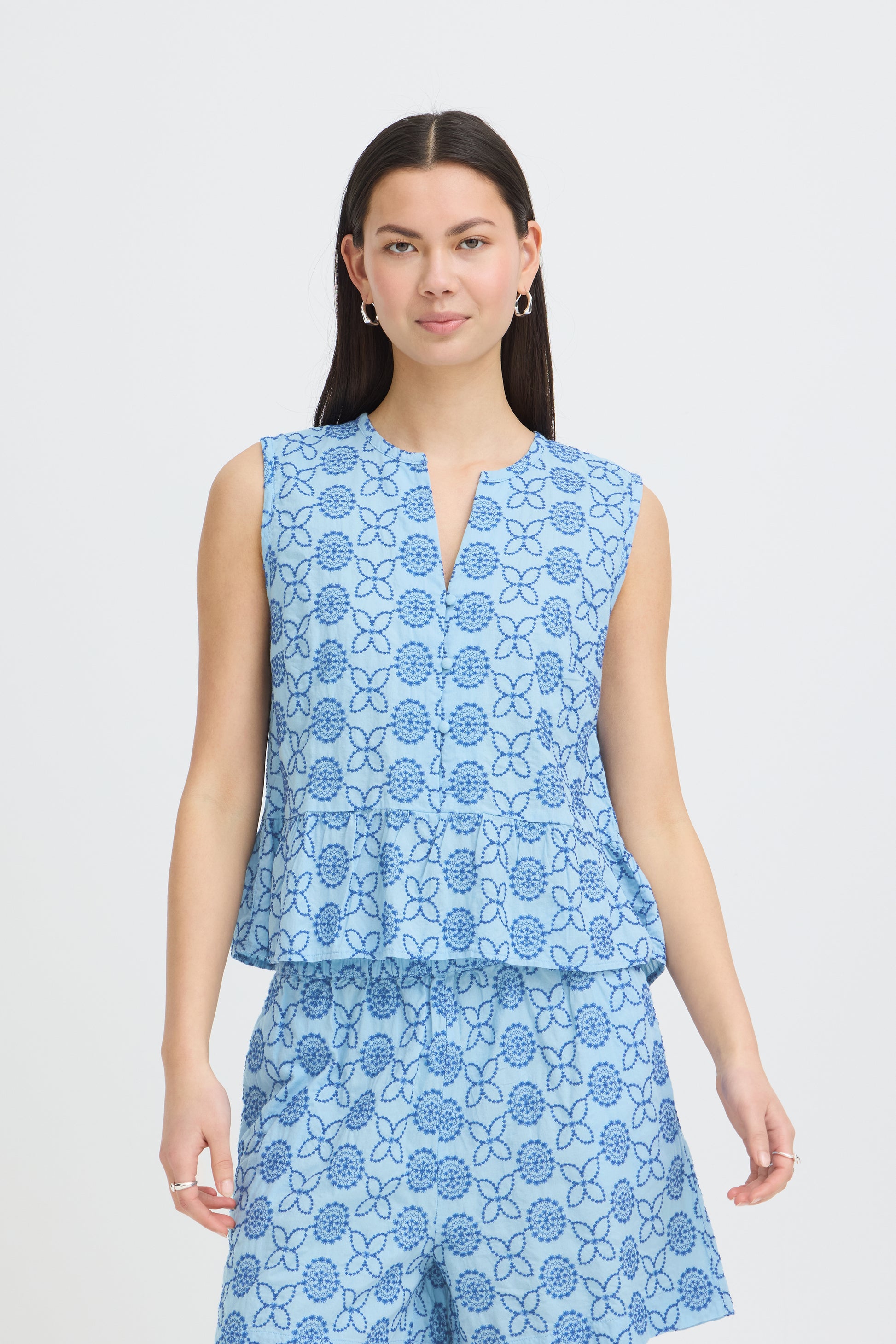 Woman wearing a blue floral sleeveless top and skirt on a white background