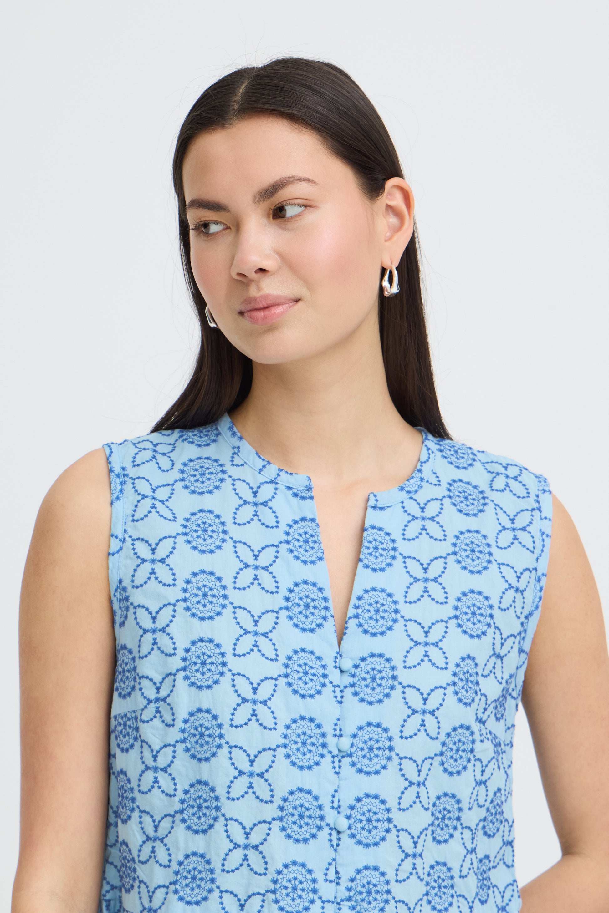 Woman wearing a blue floral sleeveless top against a light gray background