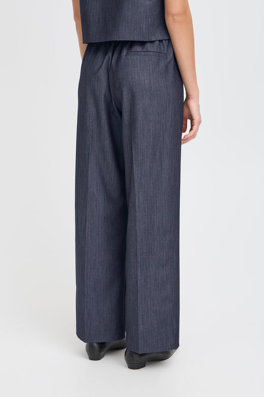 Person wearing dark gray wide-leg pants on a white background