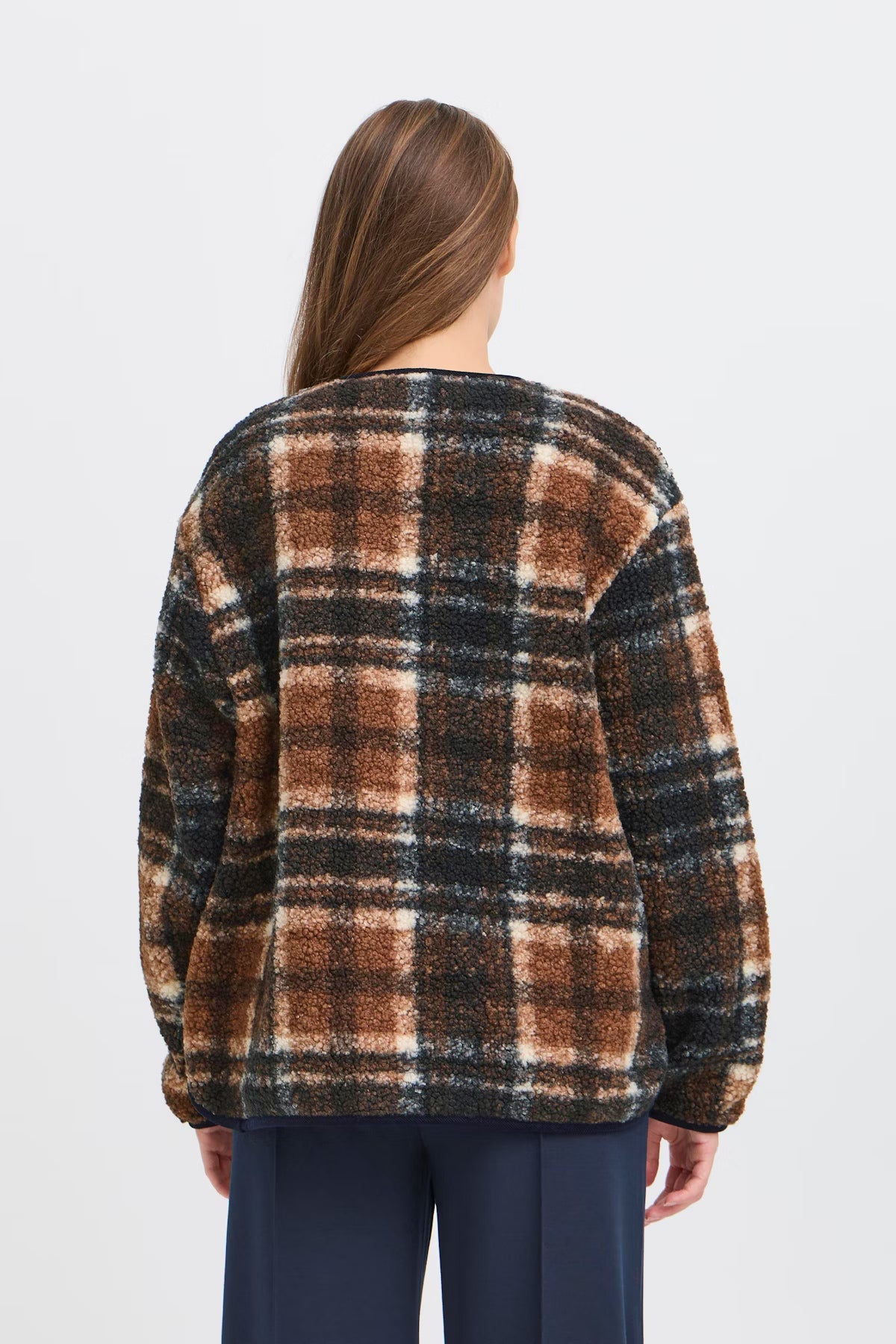 Person wearing a plaid sweater with a neutral background