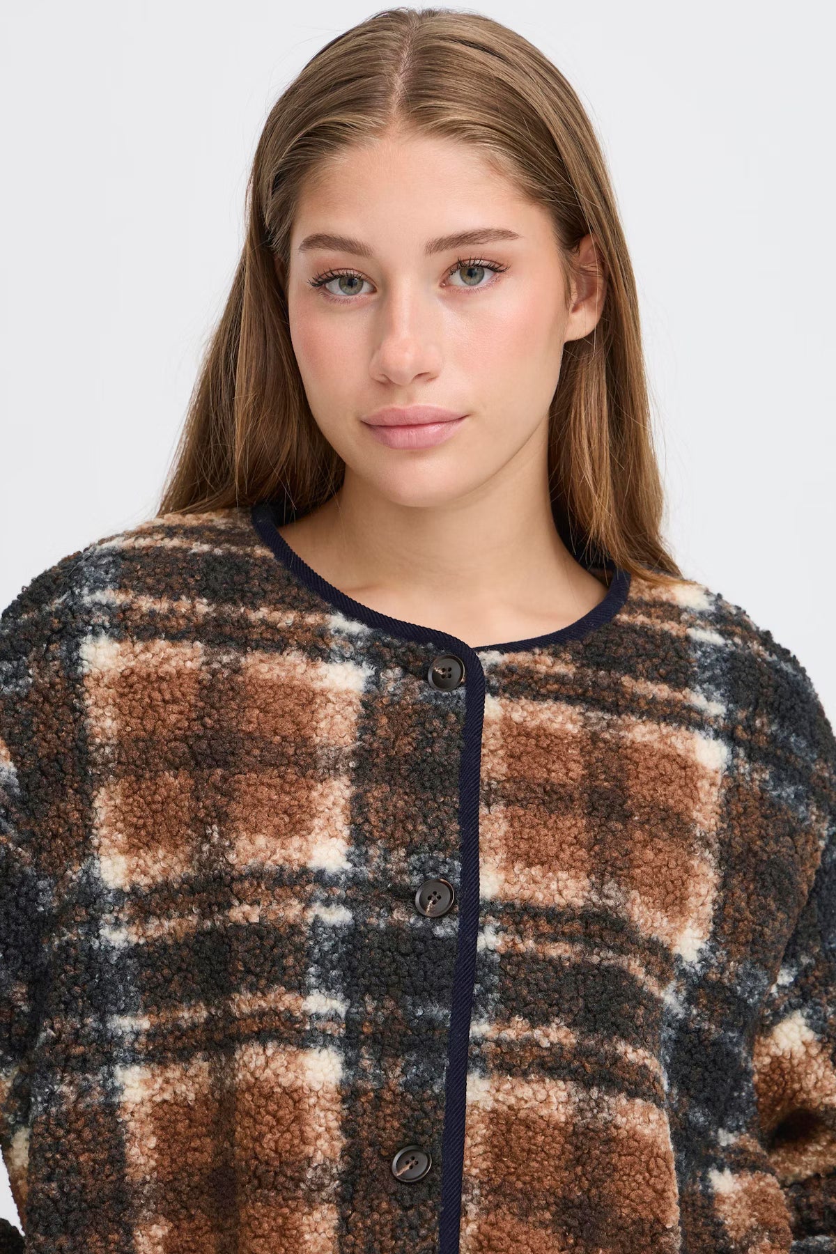Woman wearing a plaid shirt with a neutral background