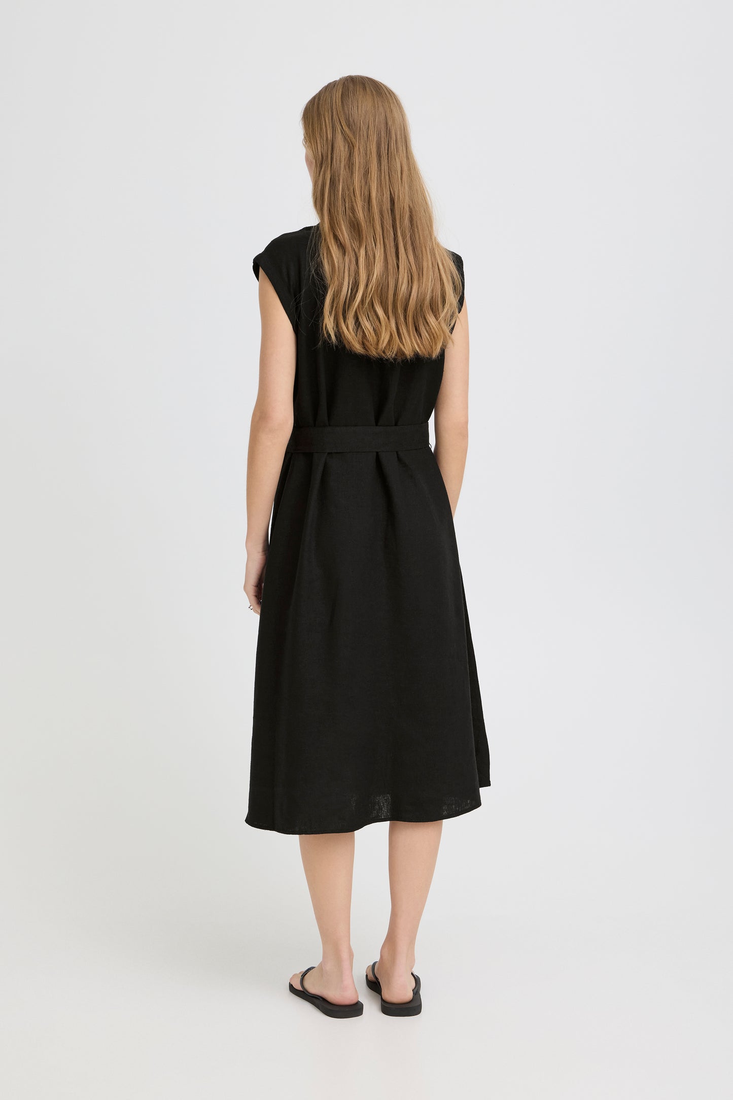 Person wearing a black sleeveless dress on a white background