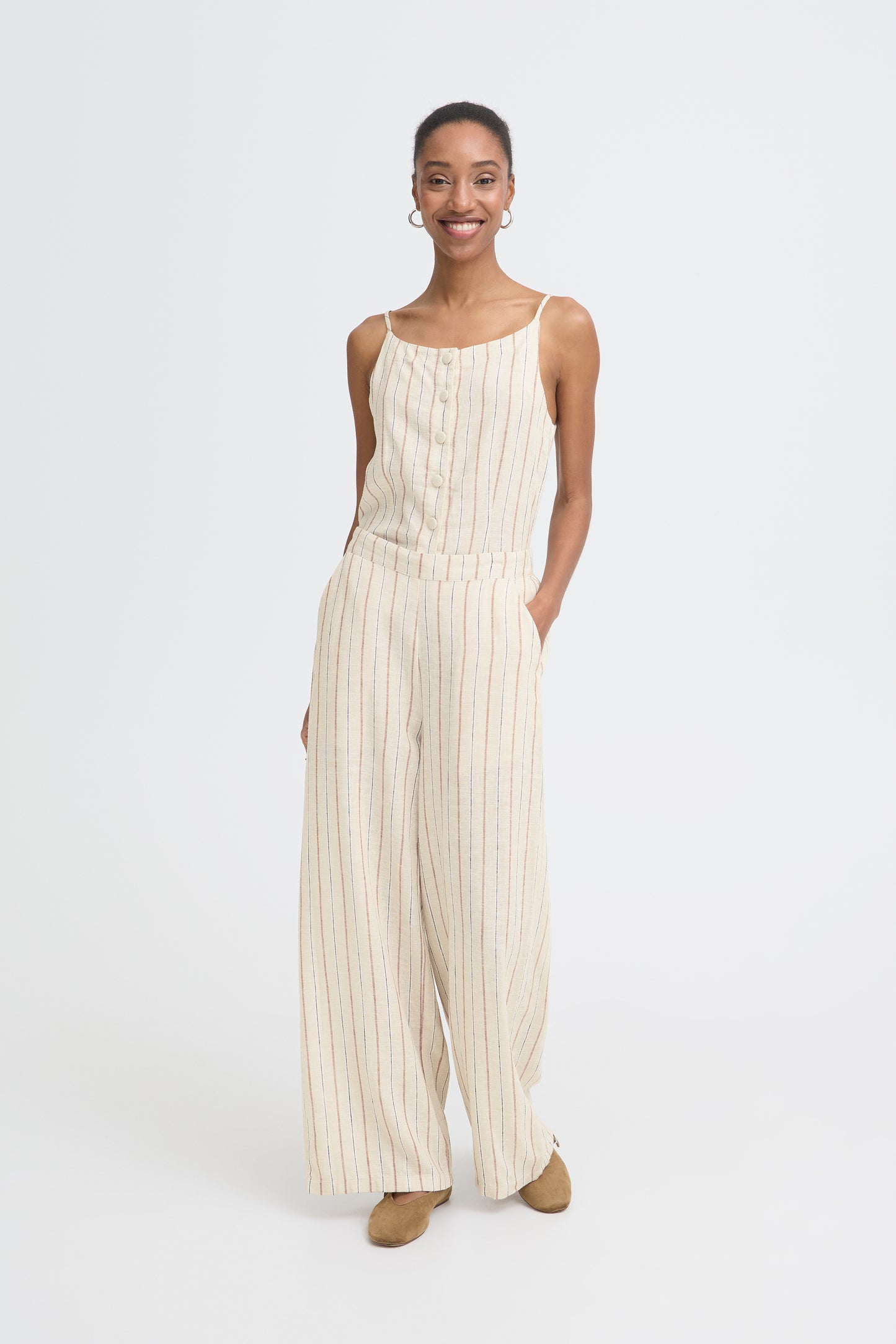 Woman wearing a white striped jumpsuit on a white background