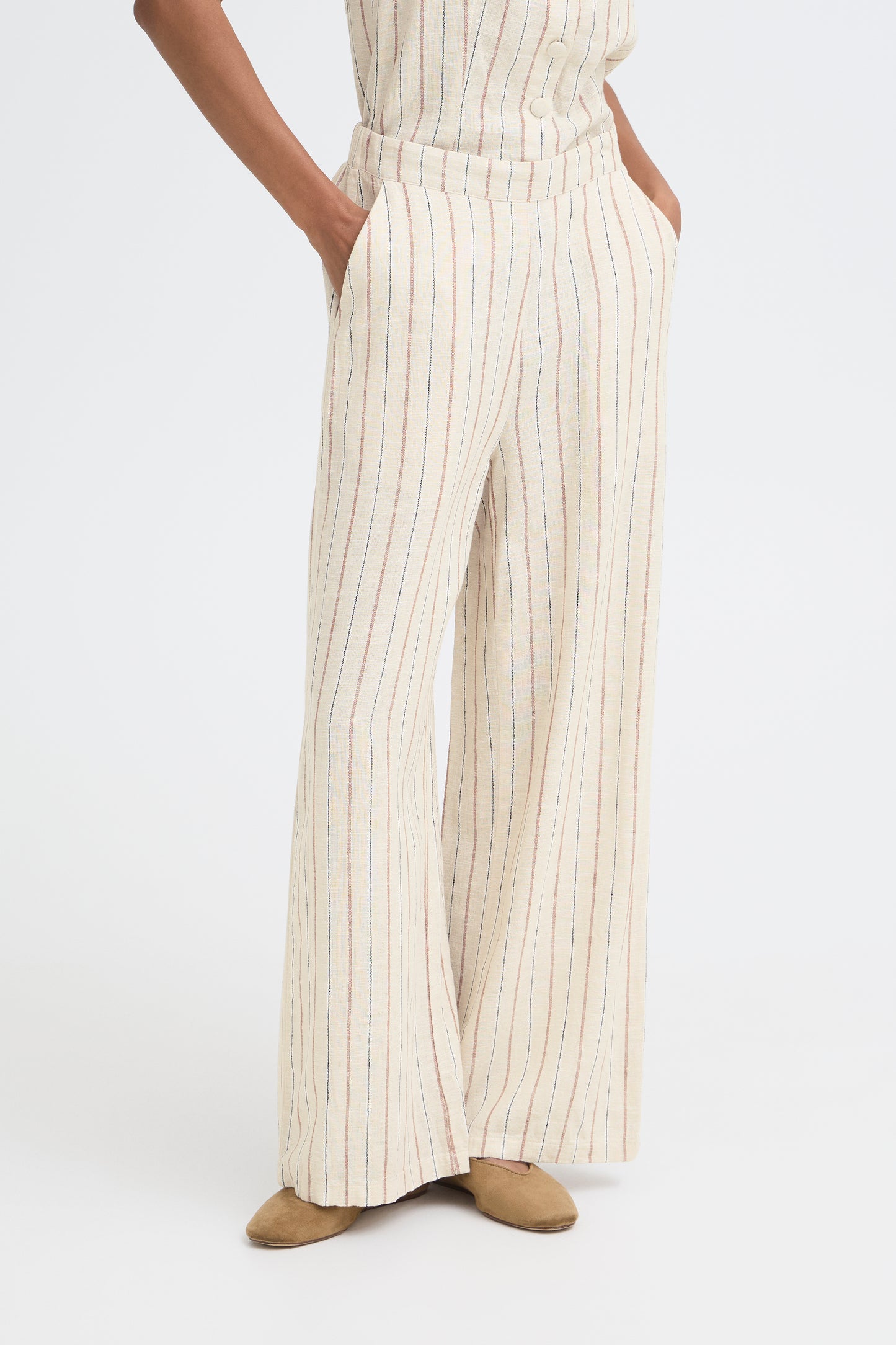 Person wearing a white and beige striped outfit with wide-leg pants on a white background