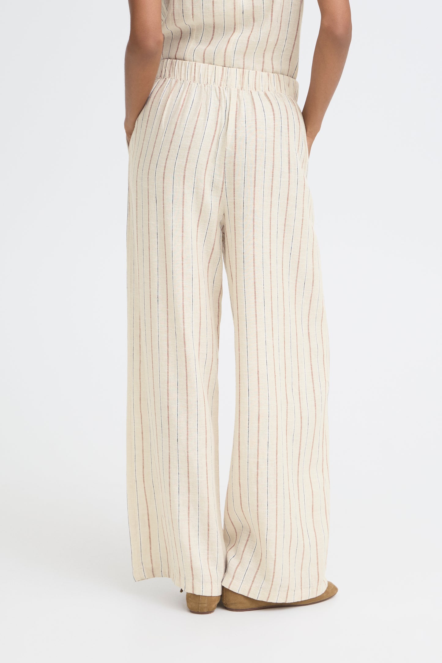 Person wearing a white and beige striped jumpsuit on a white background