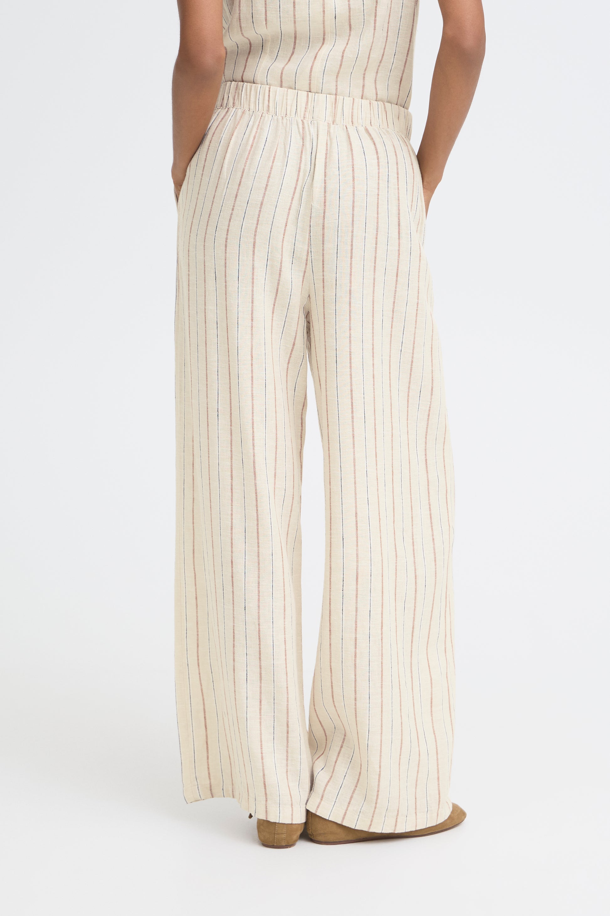 Person wearing a white and beige striped jumpsuit on a white background