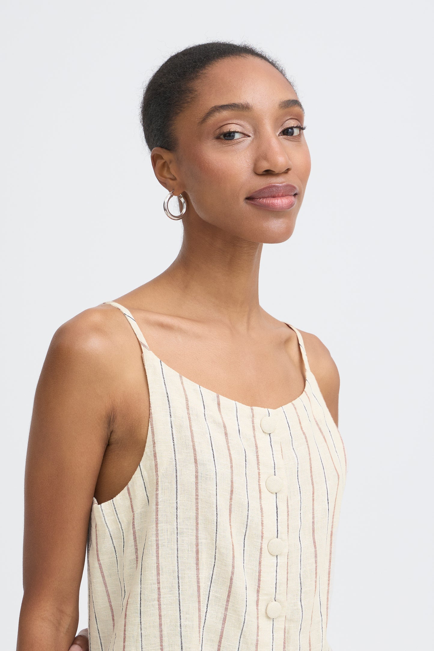 Woman wearing a beige sleeveless top against a plain background
