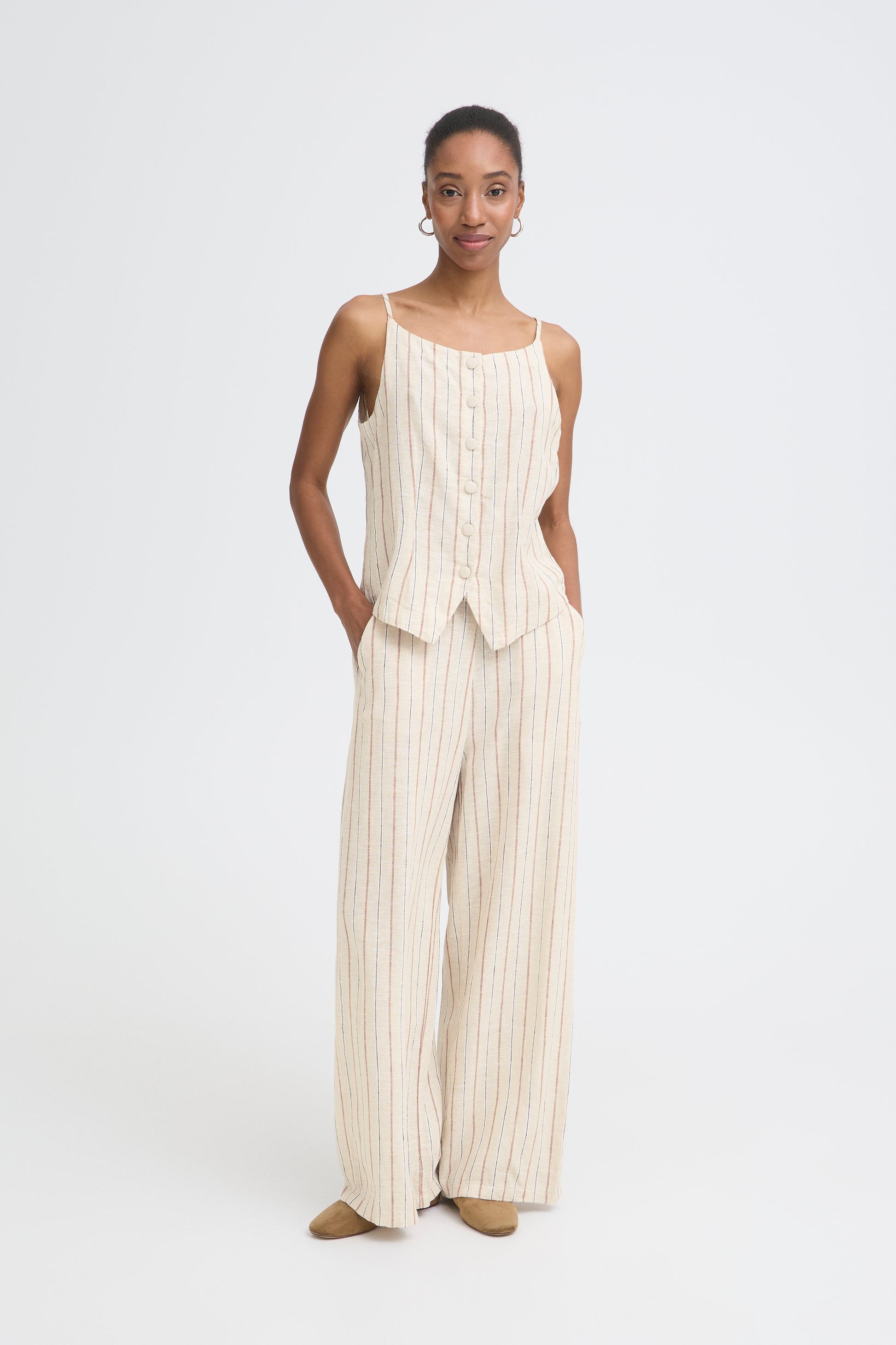 Woman wearing a white sleeveless top and wide-leg pants on a white background
