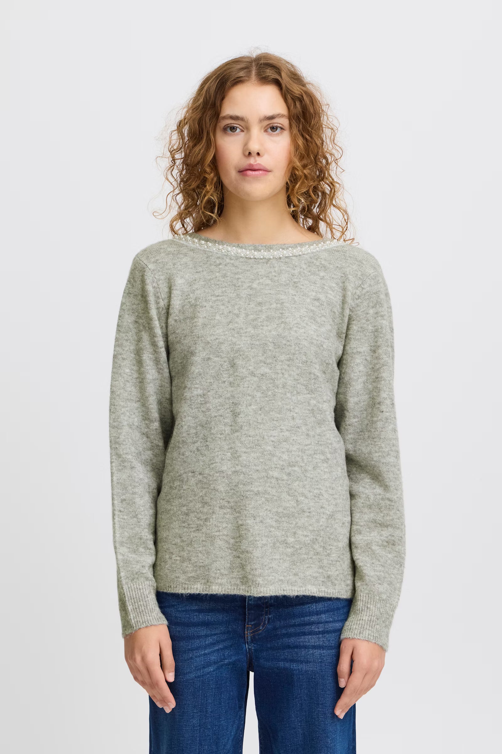 Woman wearing a gray sweater and blue jeans on a white background