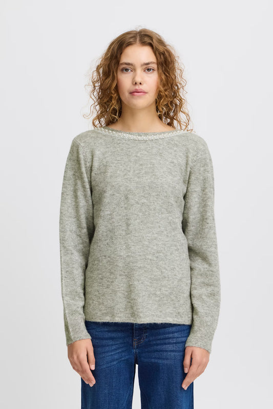 Woman wearing a gray sweater and blue jeans on a white background