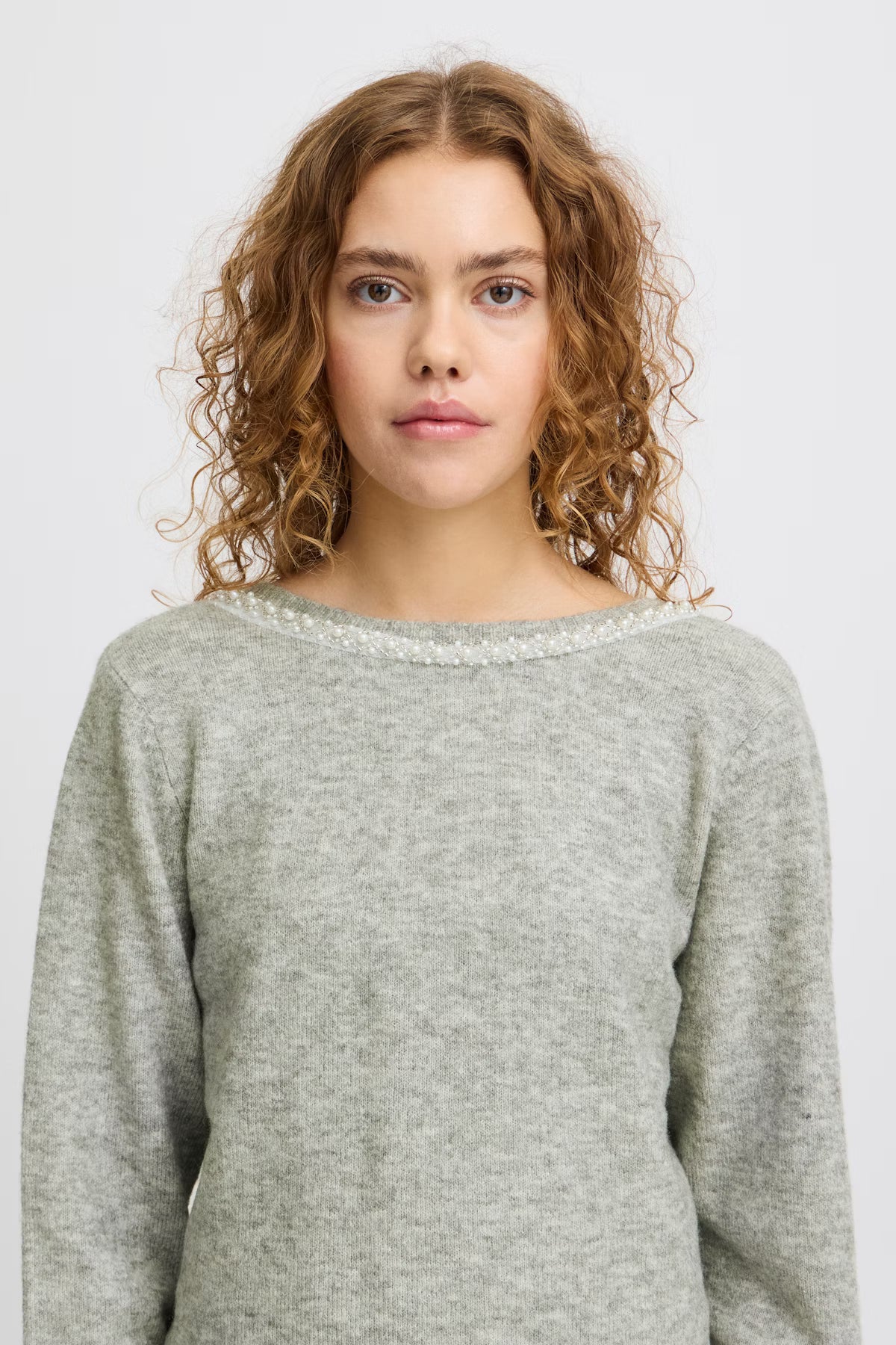 Woman wearing a gray sweater with a white background