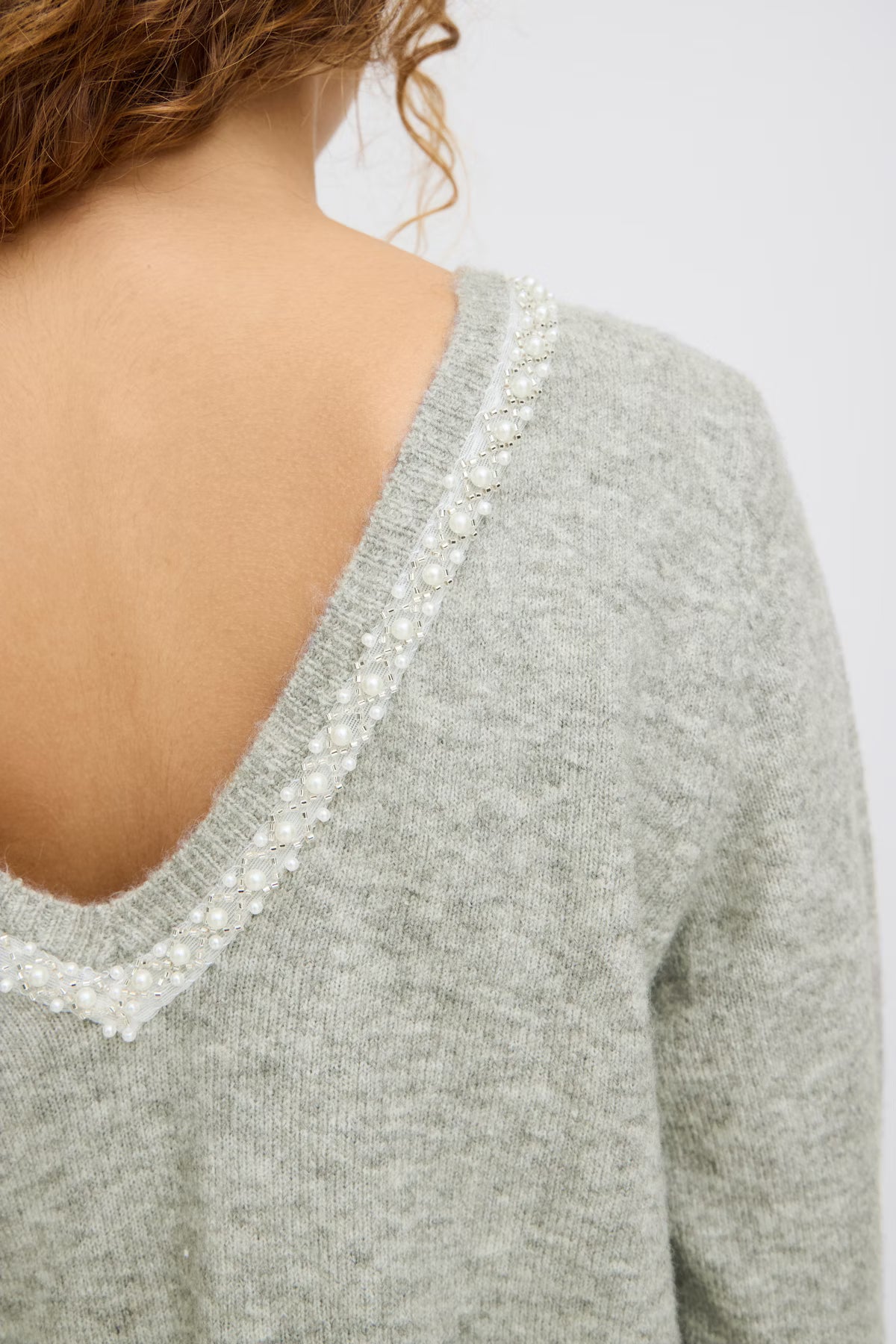 Gray sweater with pearl embellishments on a plain background