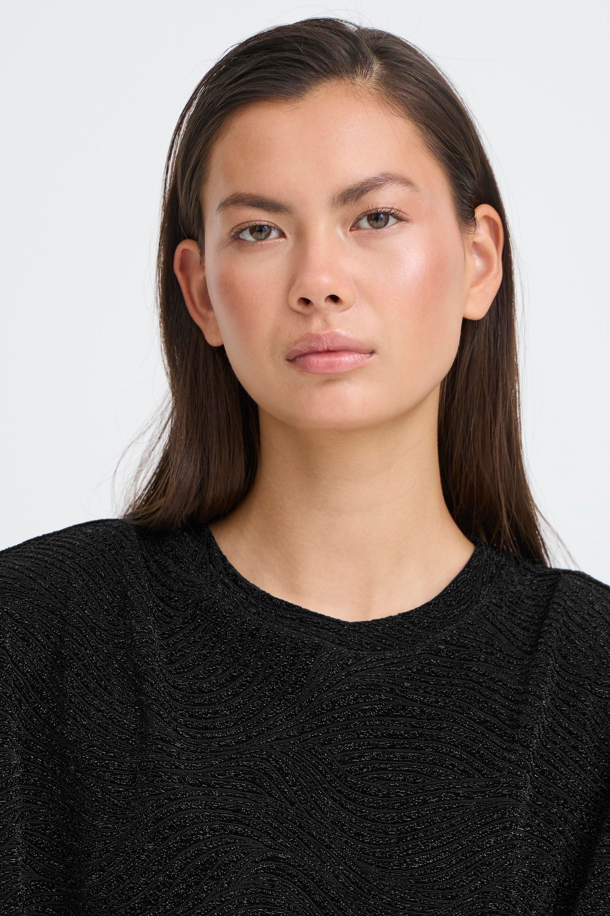 Woman wearing a black textured sweater against a white background