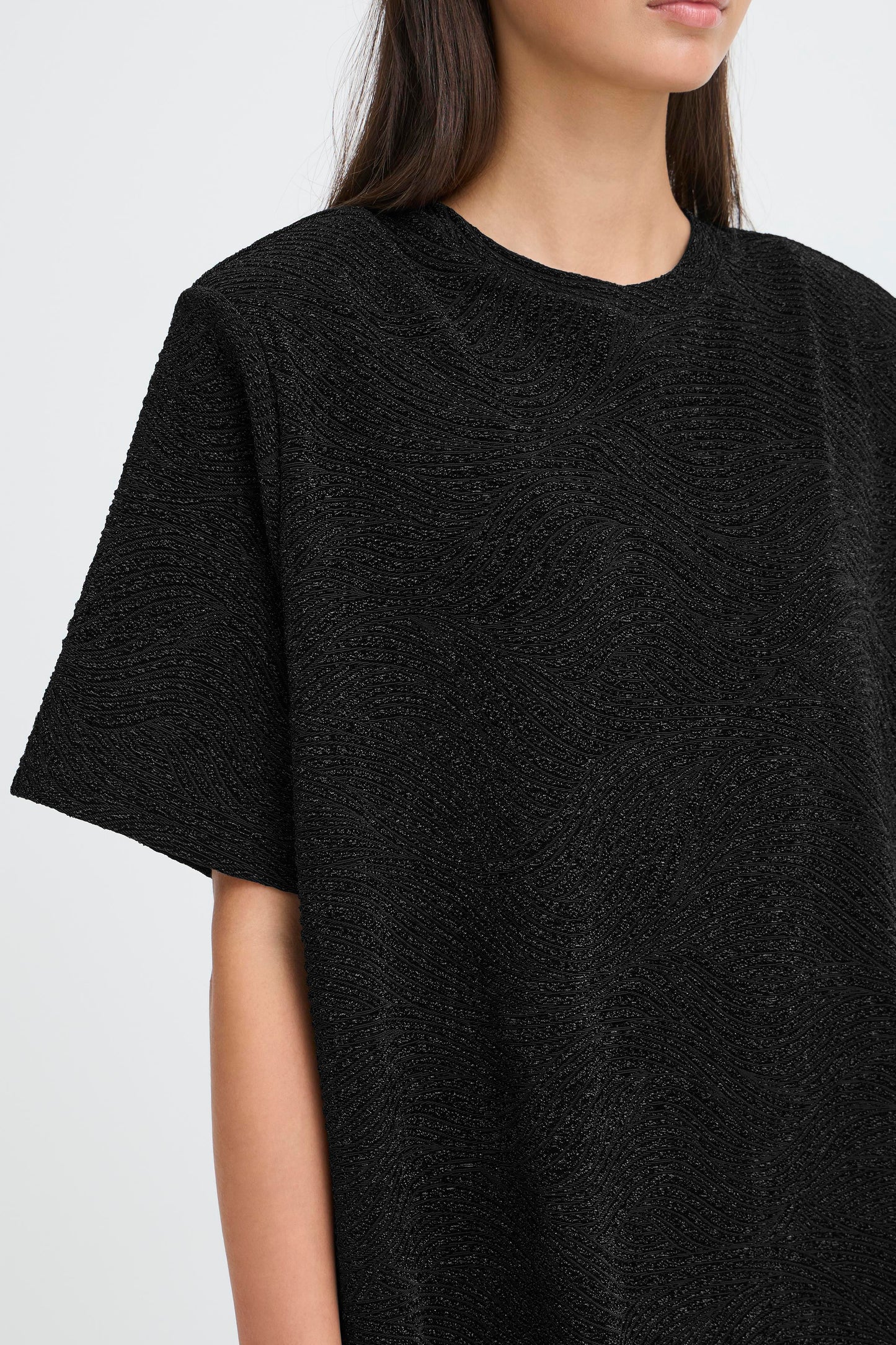Person wearing a black textured dress against a white background