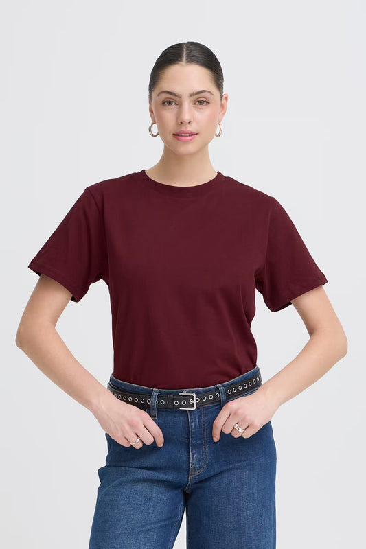 Woman wearing a maroon t-shirt and blue jeans on a white background
