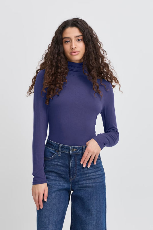 Woman wearing a blue turtleneck and jeans on a white background