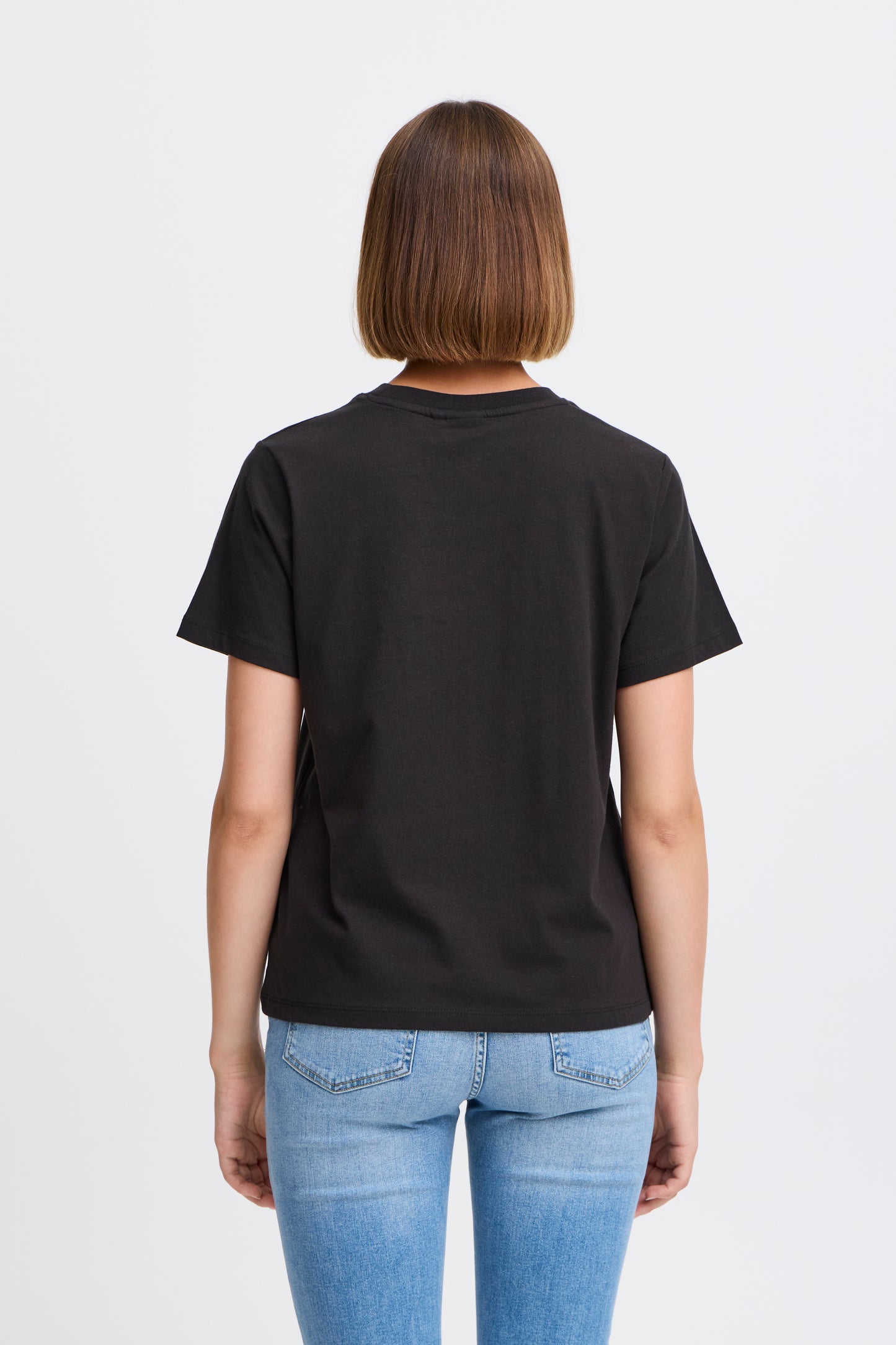 Person wearing a black t-shirt and blue jeans on a light gray background